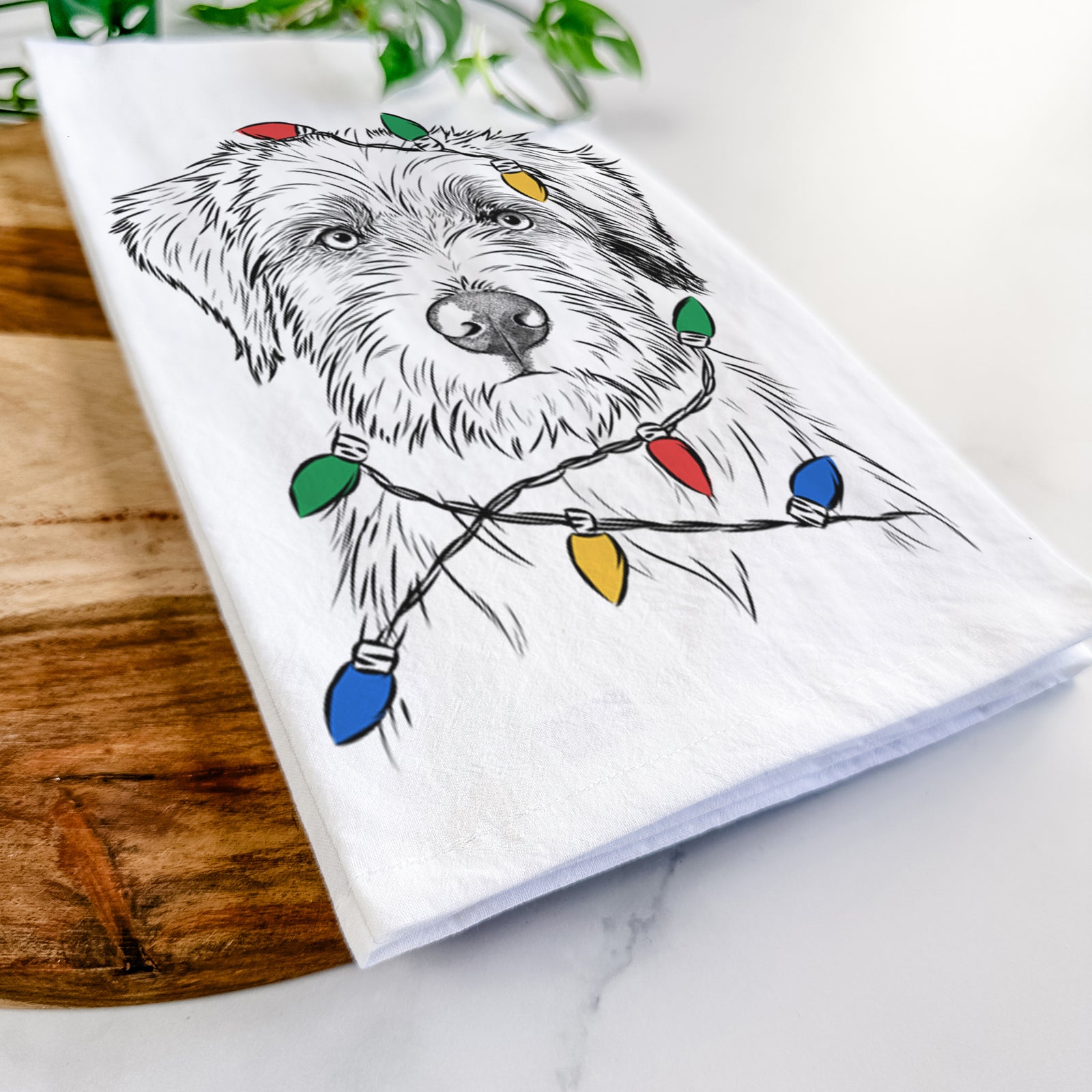 Hand-drawn sketch of Marek the Bernedoodle wrapped in Christmas lights on a tea towel