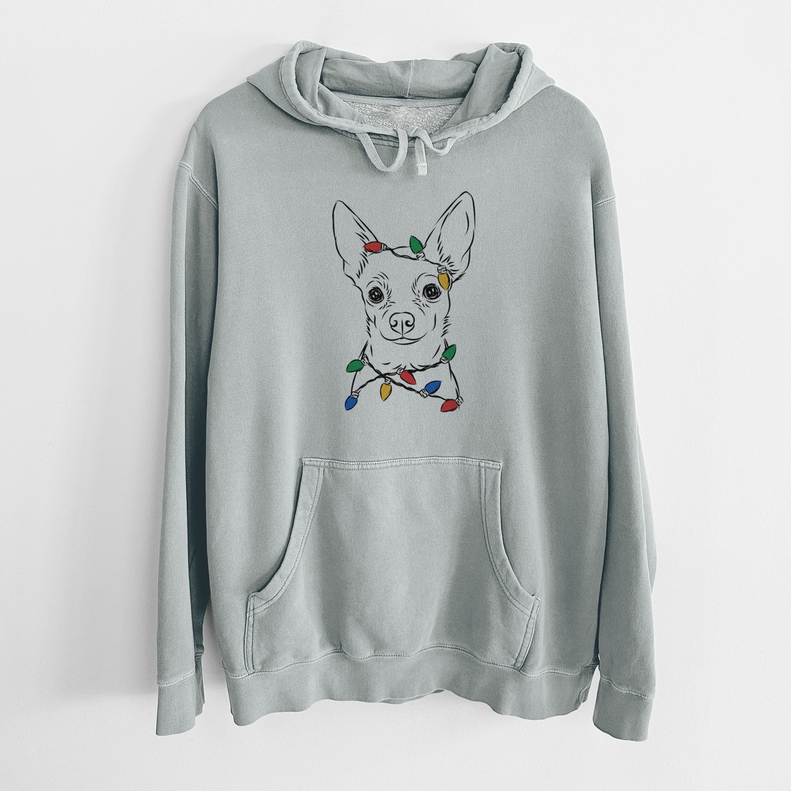 Hand-drawn sketch of Martini the Chihuahua wrapped in Christmas lights on a Sage Unisex pigment dyed hoodie