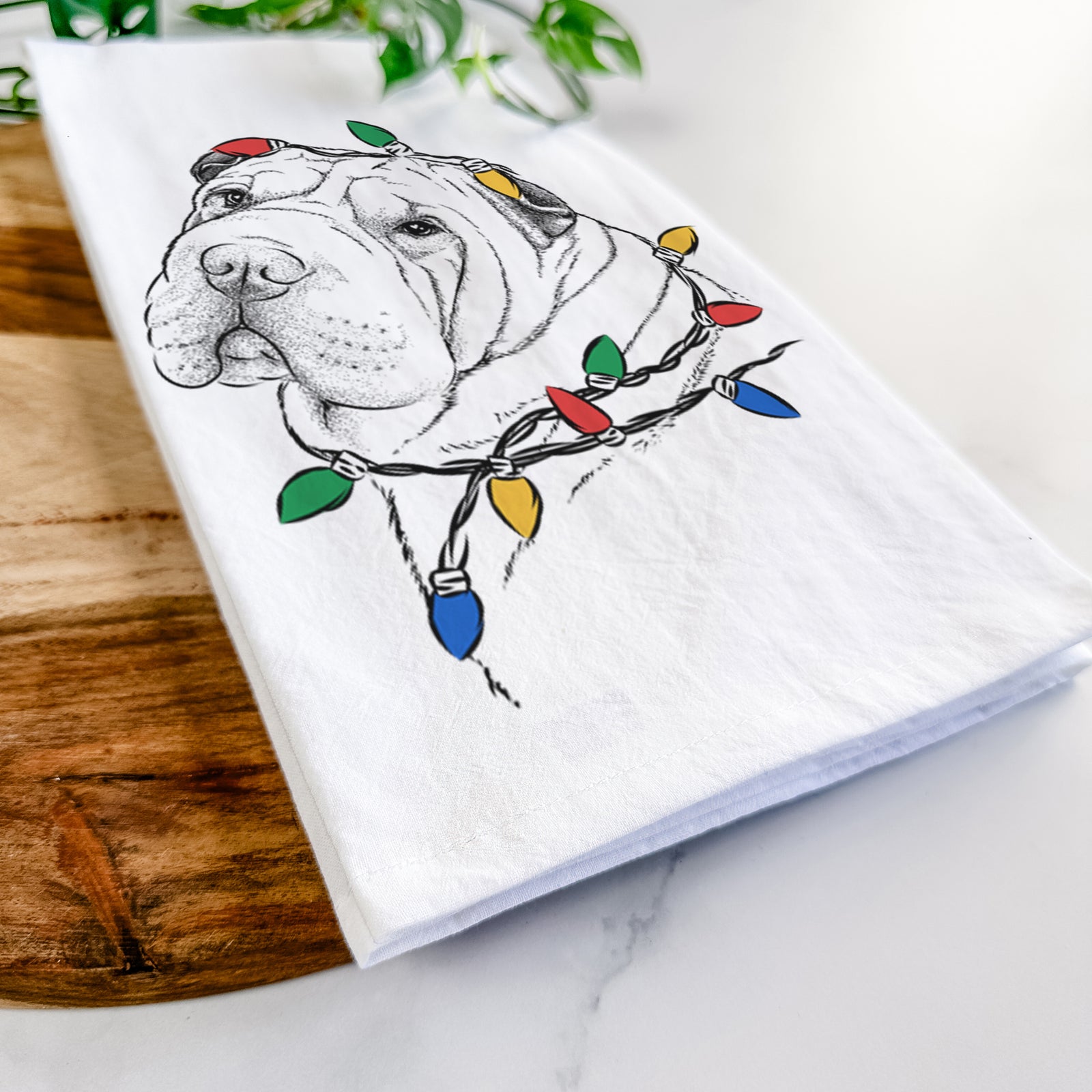 Hand-drawn sketch of Maximus the Shar Pei wrapped in Christmas lights on a tea towel