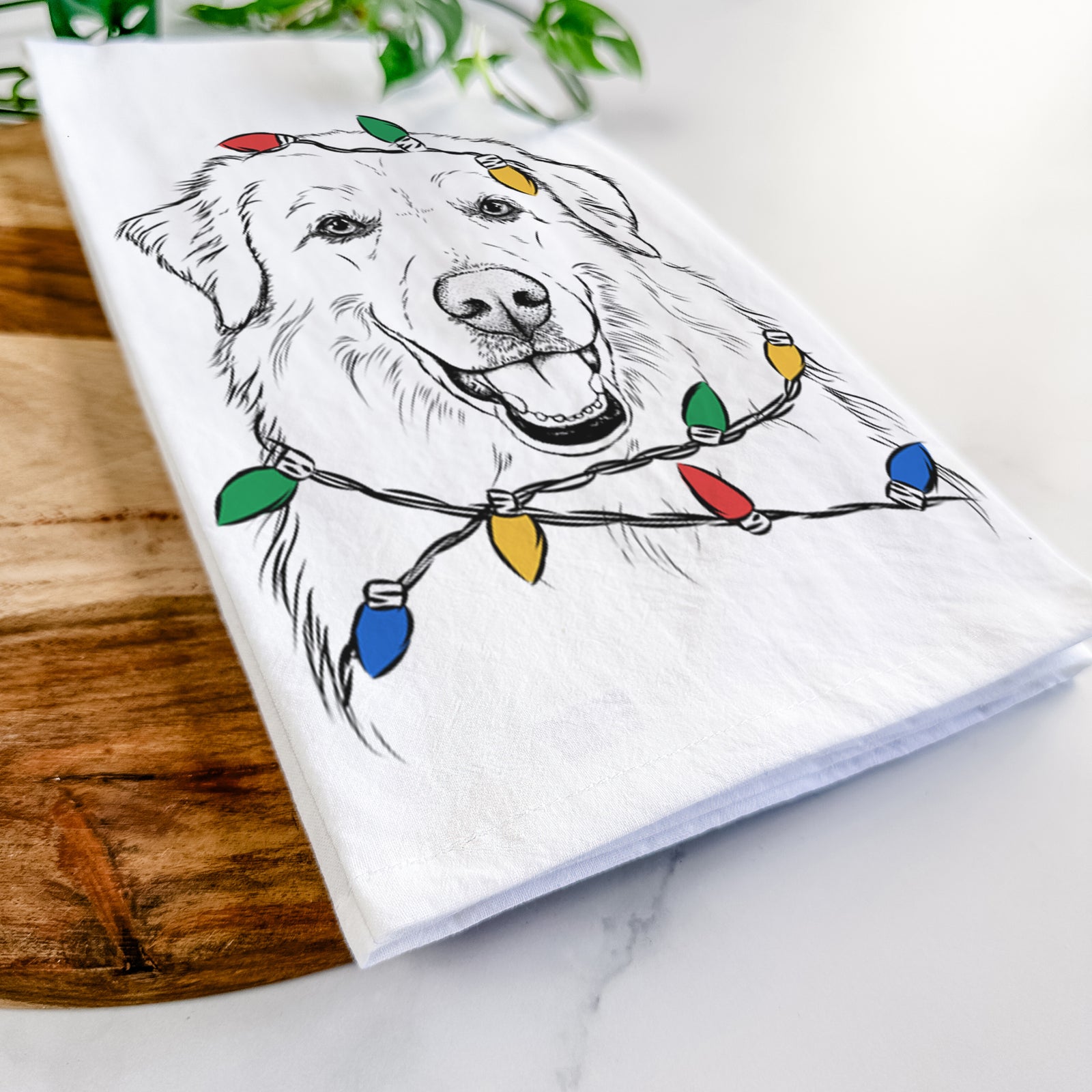 Hand-drawn sketch of Meg the Great Pyrenees wrapped in Christmas lights on a tea towel