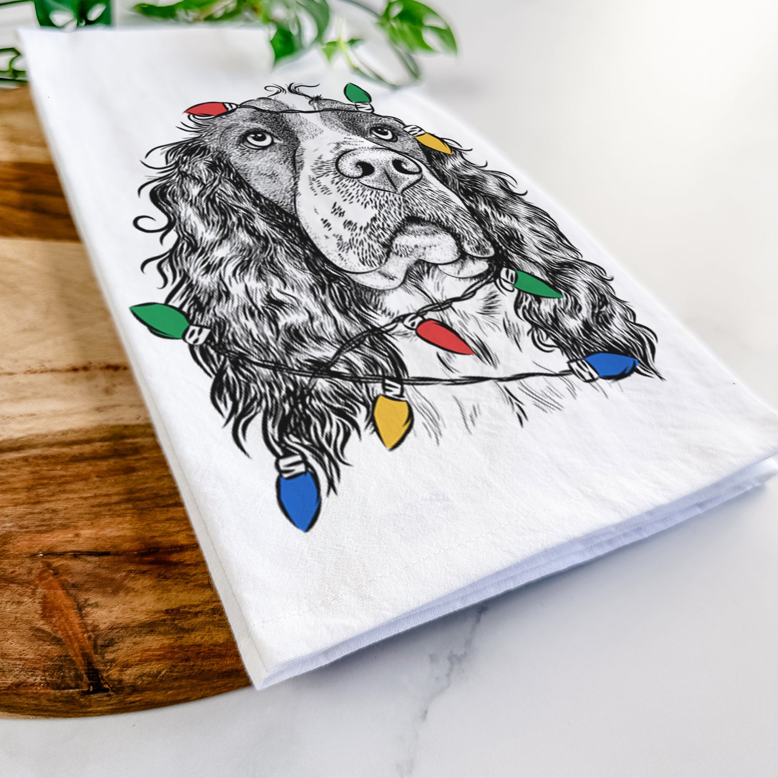 Hand-drawn sketch of Millie Mae the English Springer Spaniel wrapped in Christmas lights on a tea towel