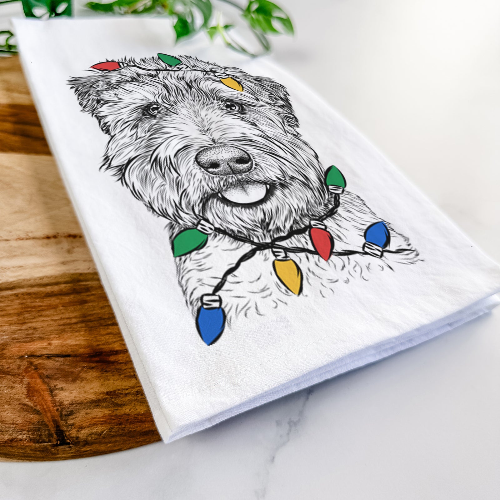 Hand-drawn sketch of Milton the Soft Coated Wheaten Terrier wrapped in Christmas lights on a tea towel