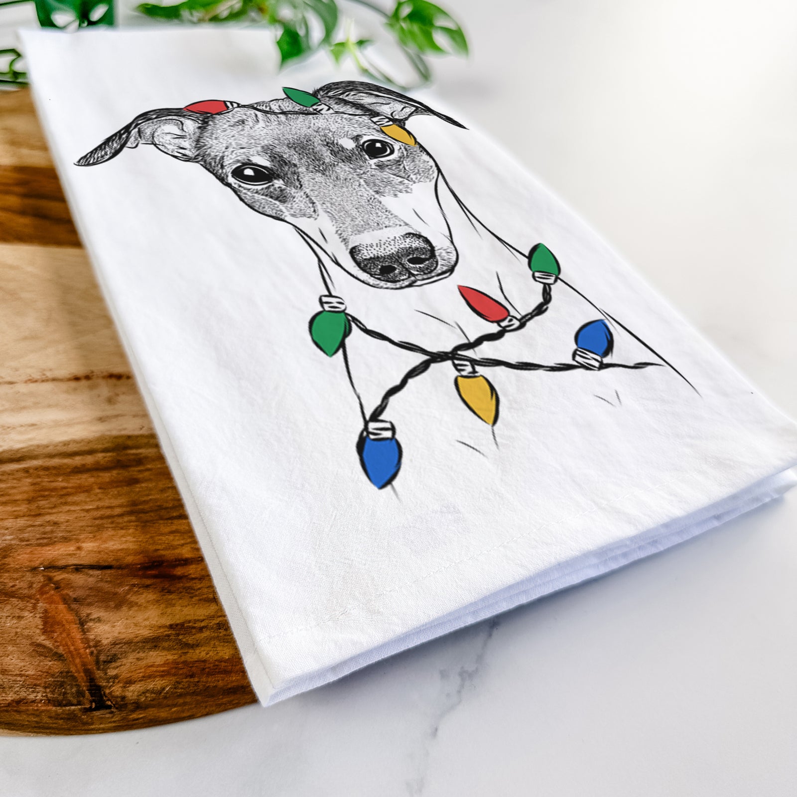 Hand-drawn sketch of Momo the Japanese Terrier wrapped in Christmas lights on a tea towel