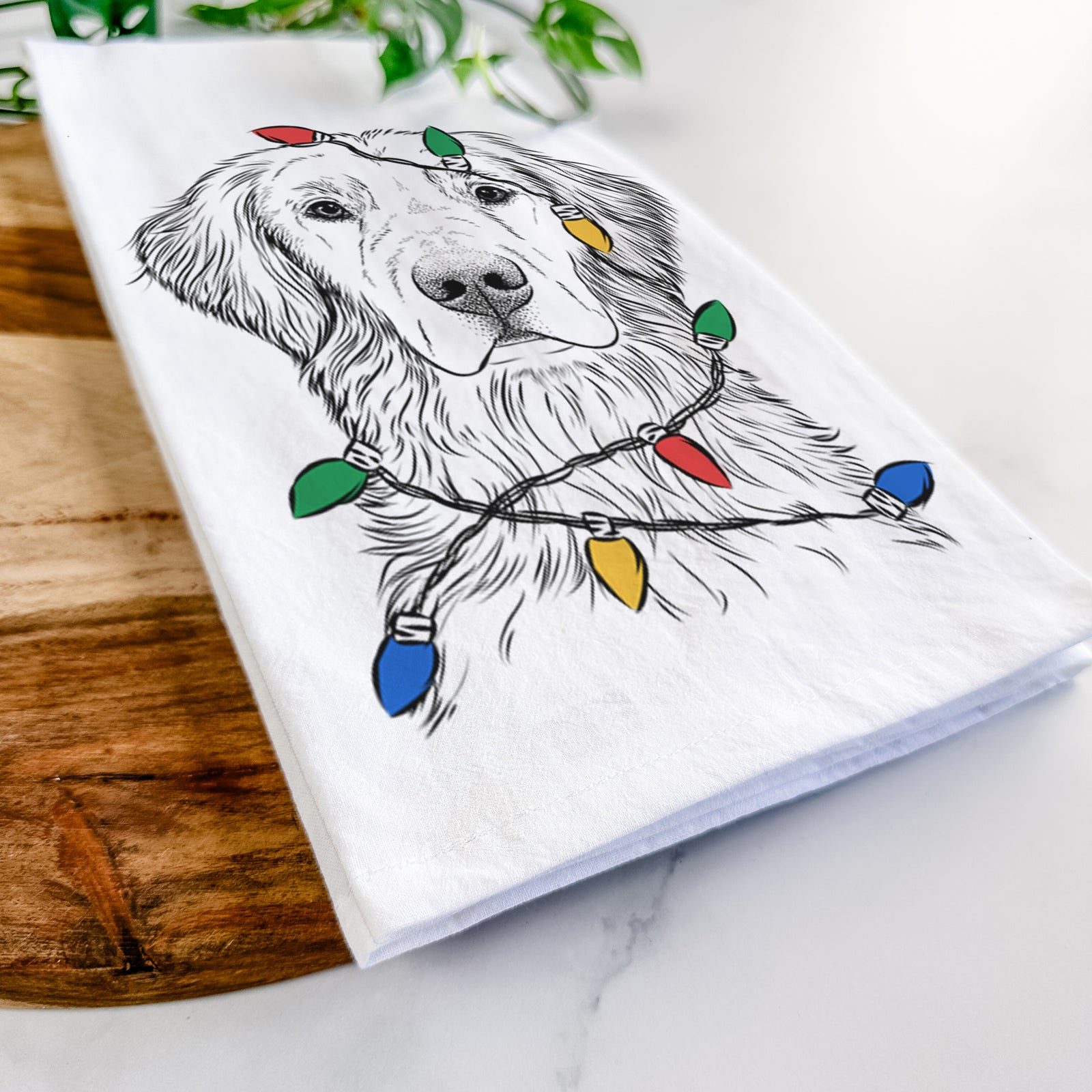 Hand-drawn sketch of Moose the Field Golden Retriever wrapped in Christmas lights on a tea towel