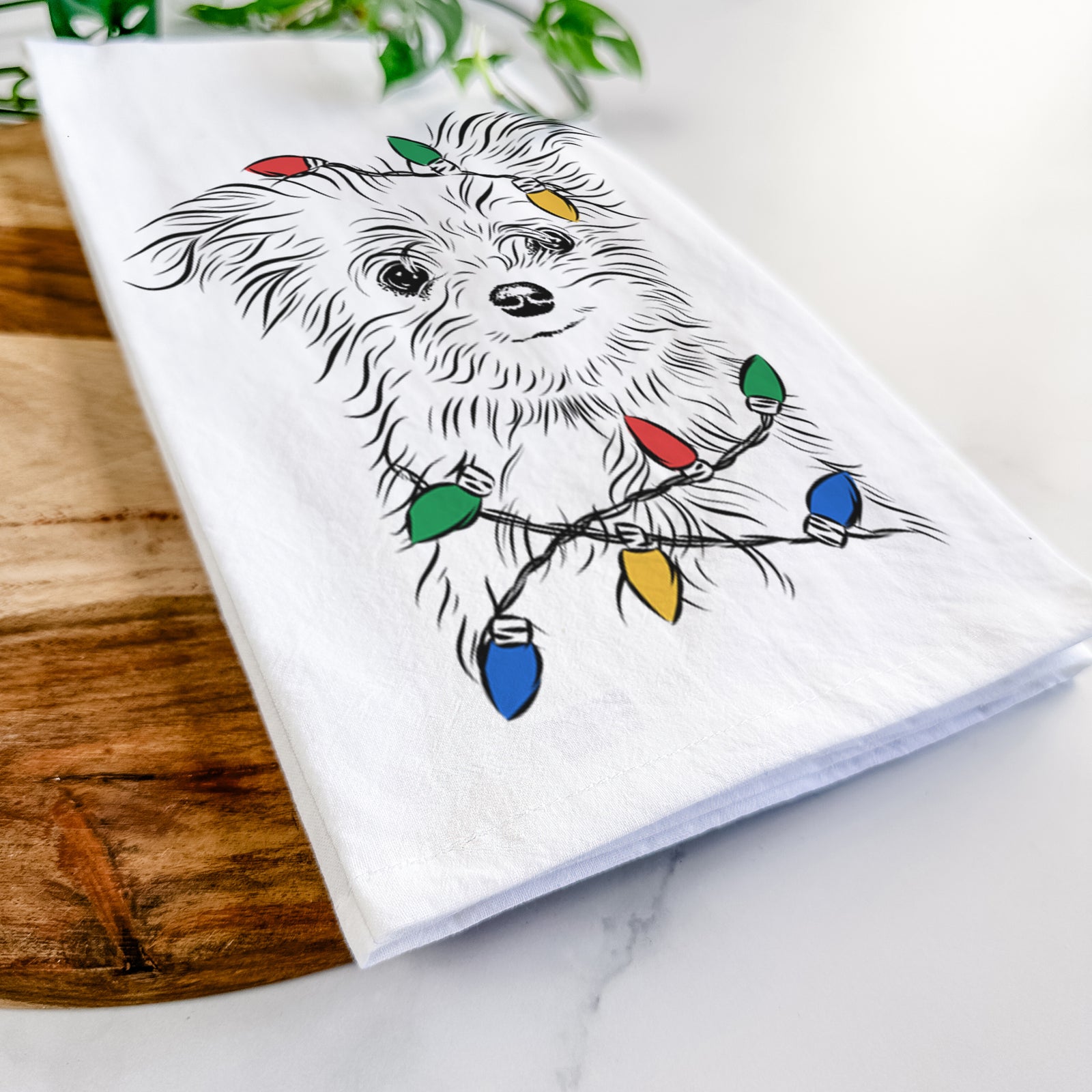 Hand-drawn sketch of Mr. Gucci Poochi the Maltese wrapped in Christmas lights on a tea towel