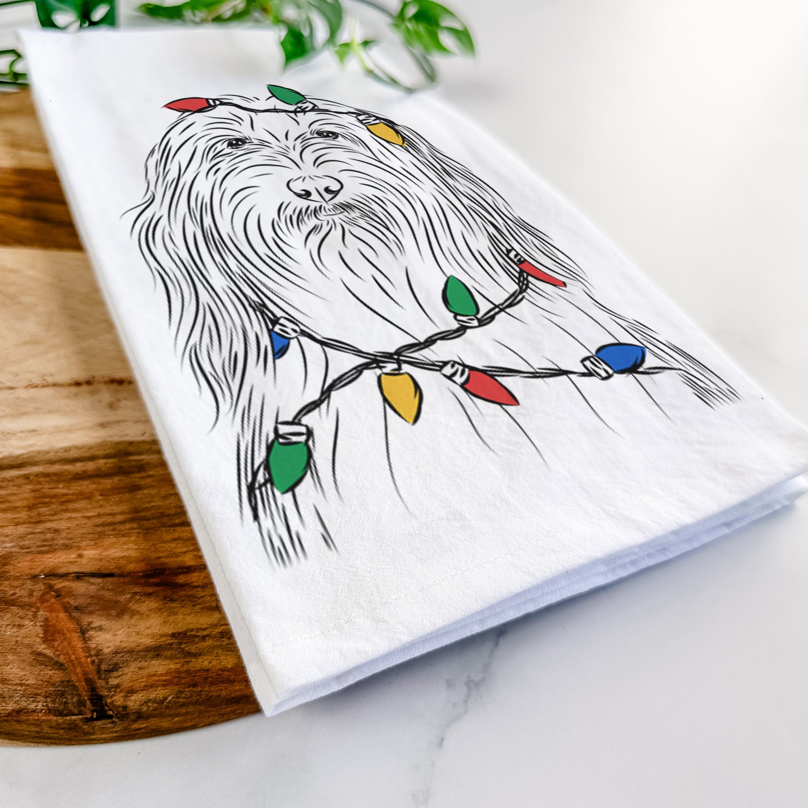 Hand-drawn sketch of Murray the Bearded Collie wrapped in Christmas lights on a tea towel
