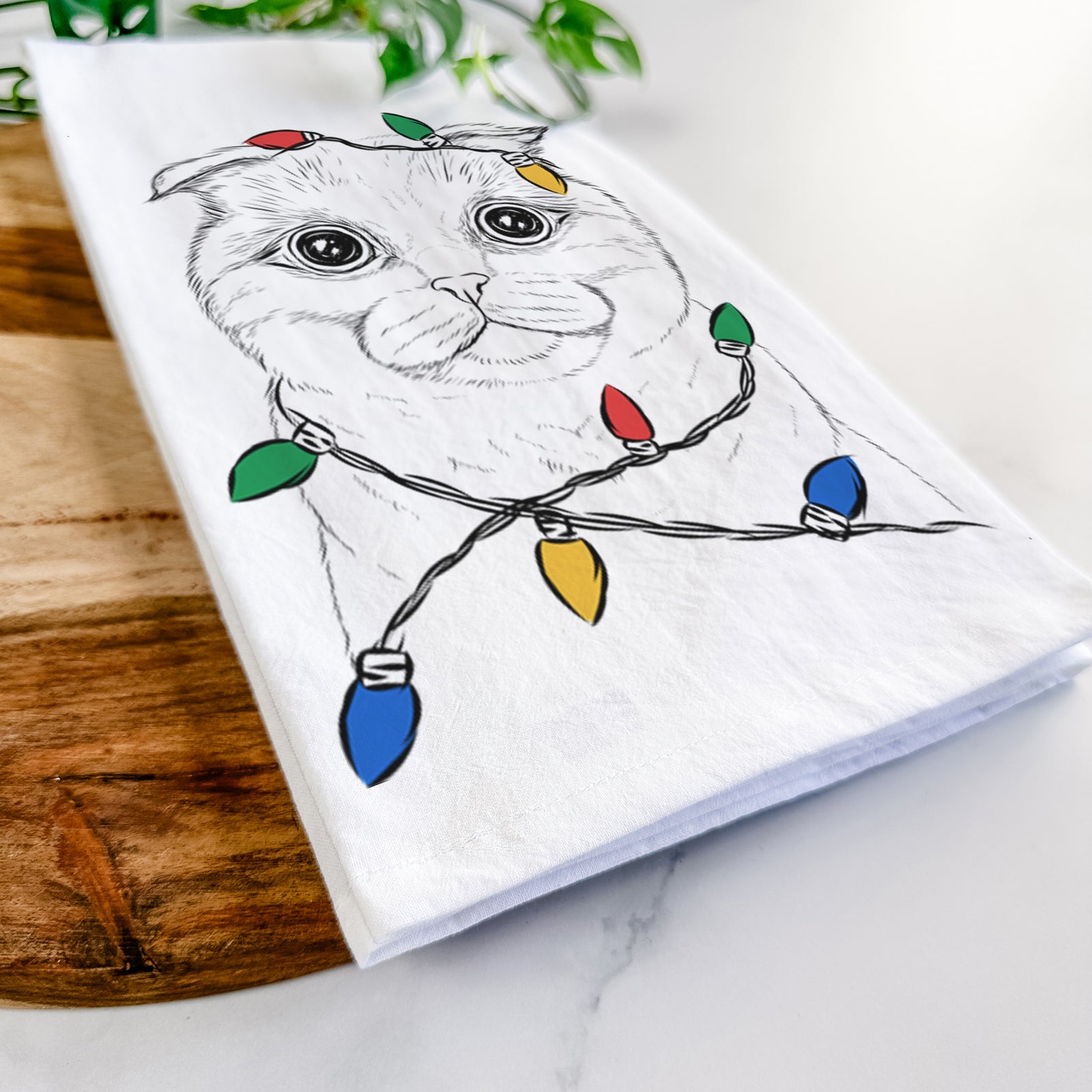 Hand-drawn sketch of Neko the Scottish Fold Cat wrapped in Christmas lights on a tea towel