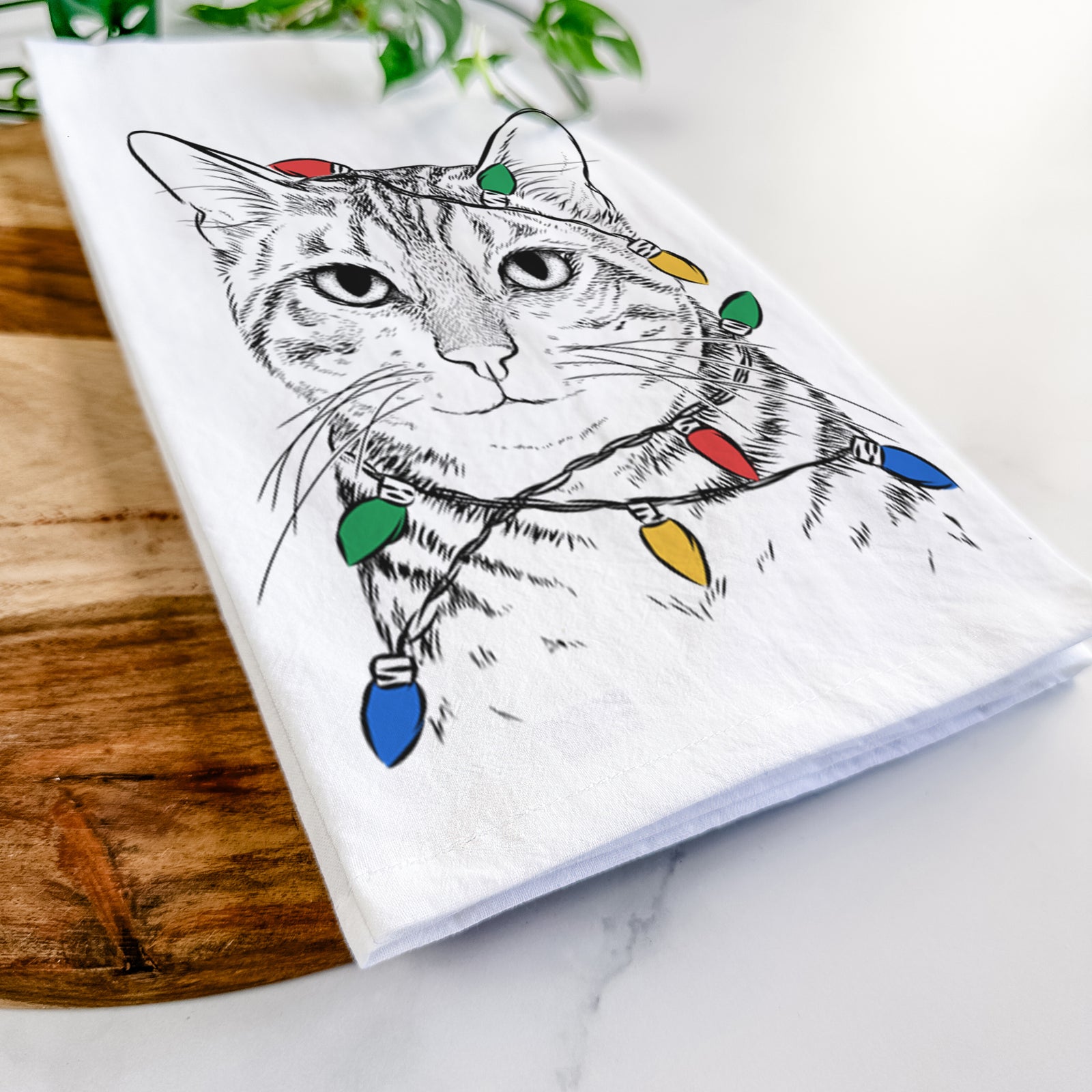 Hand-drawn sketch of Nell the Tabby Cat wrapped in Christmas lights on a tea towel