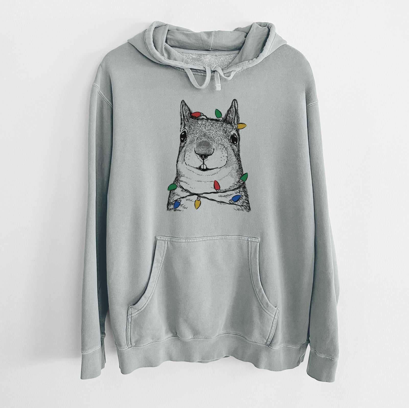 Hand-drawn sketch of Nibbles the Squirrel wrapped in Christmas lights on a Sage Unisex pigment dyed hoodie