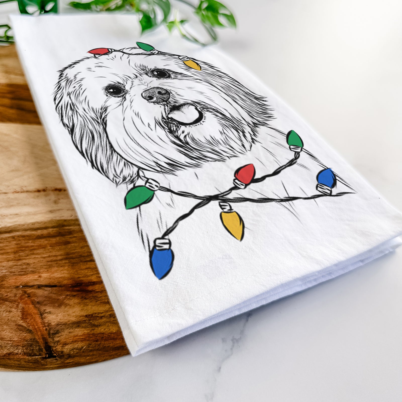 Hand-drawn sketch of Nikka the Lowchen wrapped in Christmas lights on a tea towel