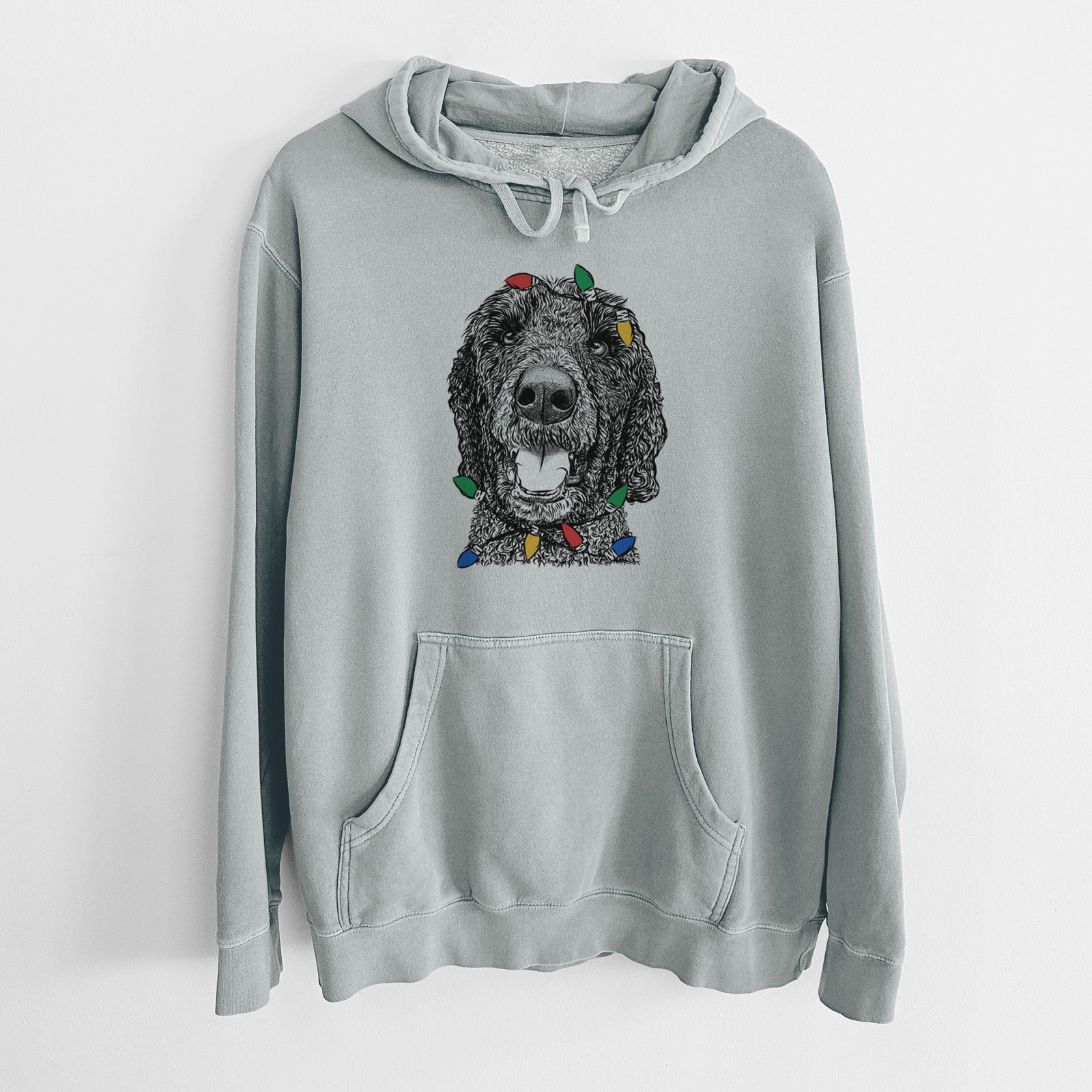 Hand-drawn sketch of Obi James the Goldendoodle wrapped in Christmas lights on a Sage Unisex pigment dyed hoodie