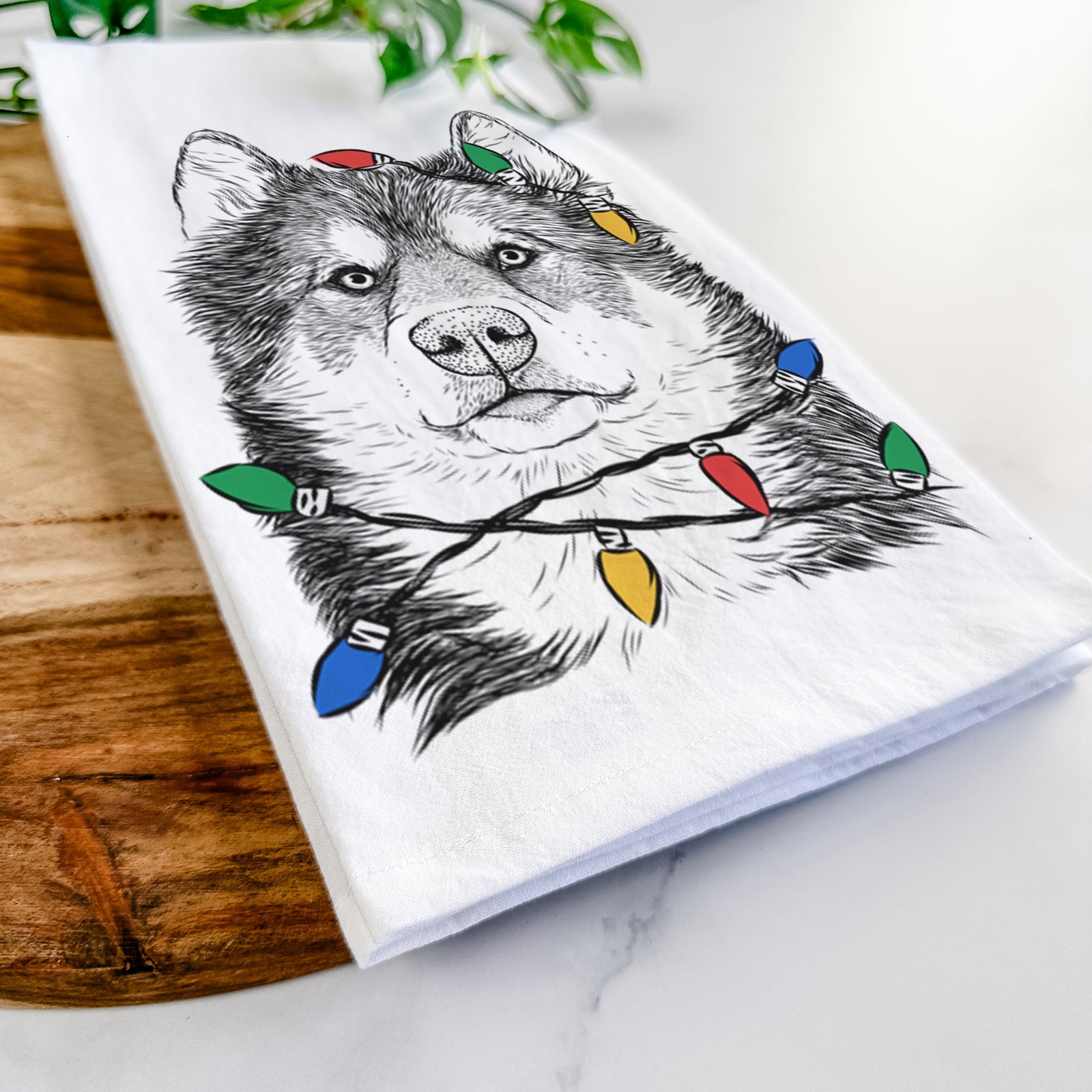 Hand-drawn sketch of Oskar the Canadian Eskimo Dog wrapped in Christmas lights on a tea towel