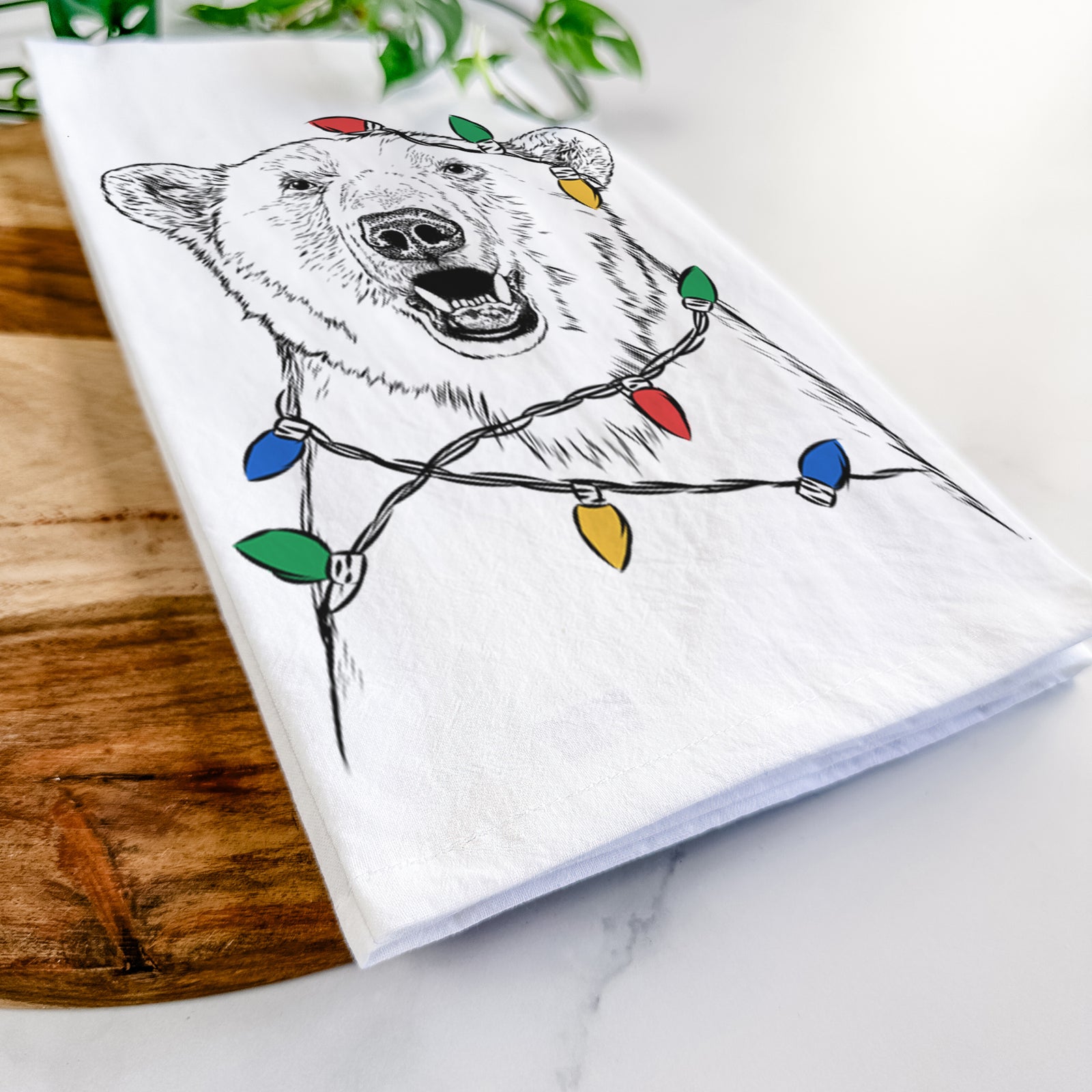 Hand-drawn sketch of Oslo the Polar Bear wrapped in Christmas lights on a tea towel