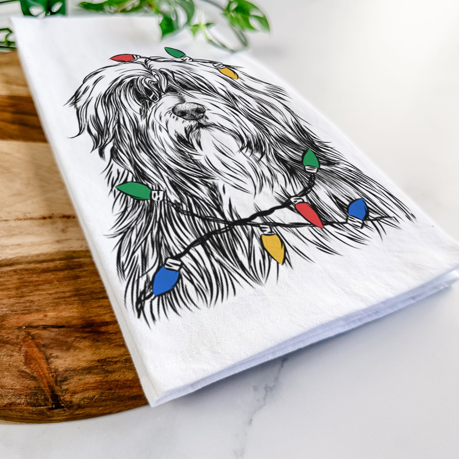 Hand-drawn sketch of Otto the Polish Lowland Sheepdog wrapped in Christmas lights on a tea towel
