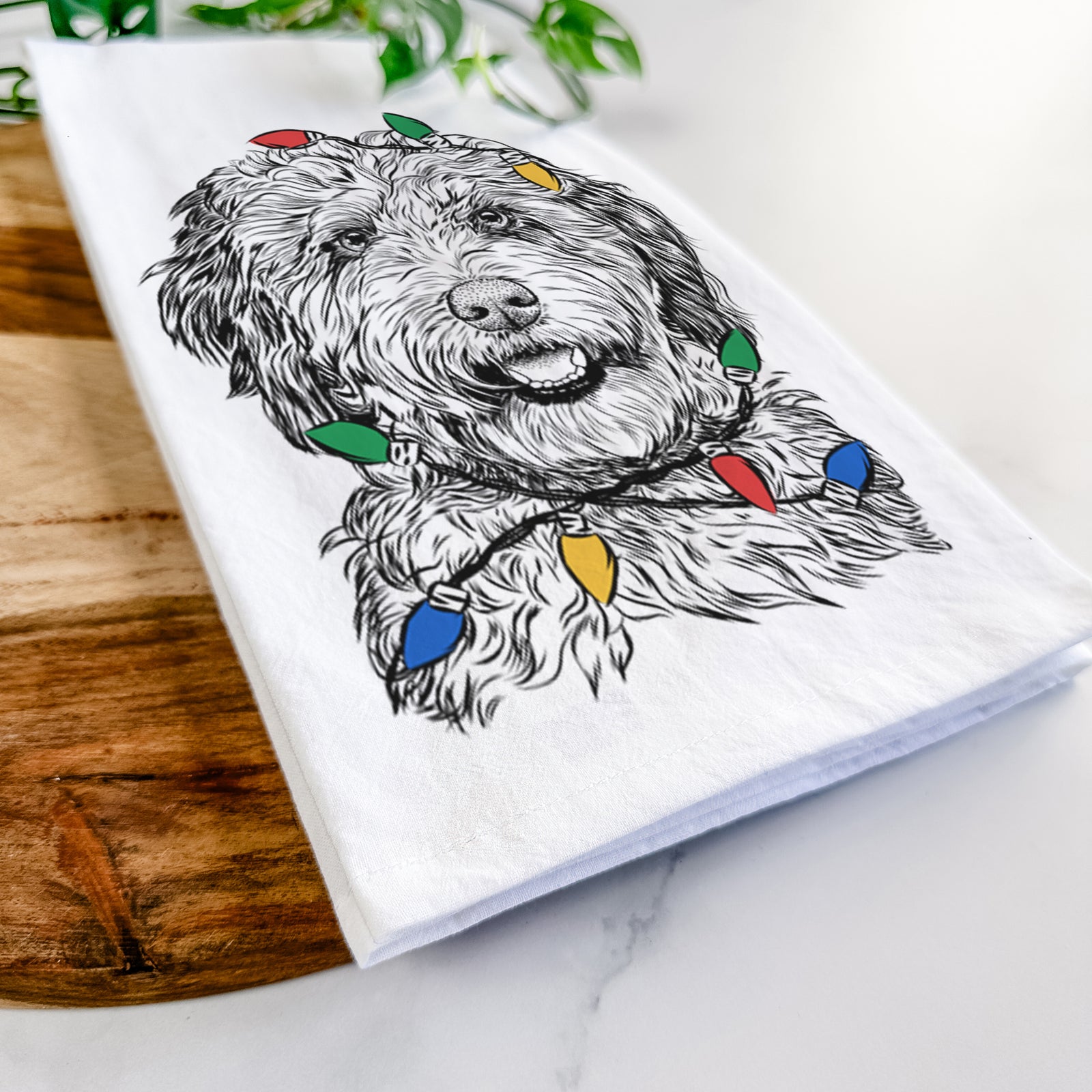 Hand-drawn sketch of Palmer the Aussiedoodle wrapped in Christmas lights on a tea towel