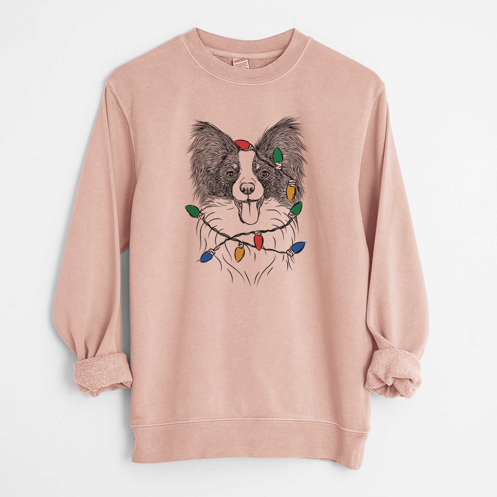 Hand-drawn sketch of Patrick the Papillon wrapped in Christmas lights on a Dusty Pink Unisex pigment dyed crew sweatshirt
