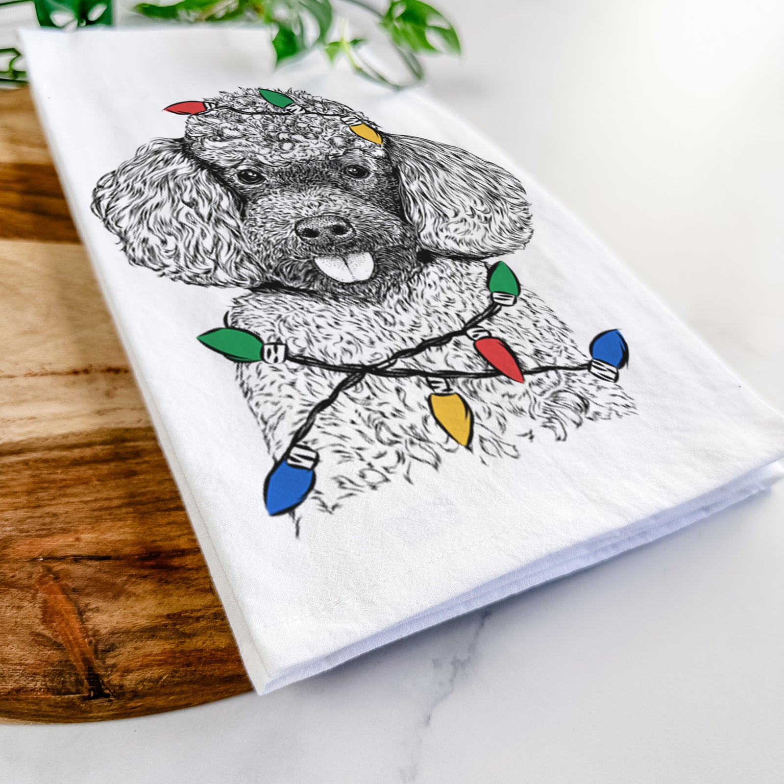 Hand-drawn sketch of George the Toy Poodle wrapped in Christmas lights on a tea towel