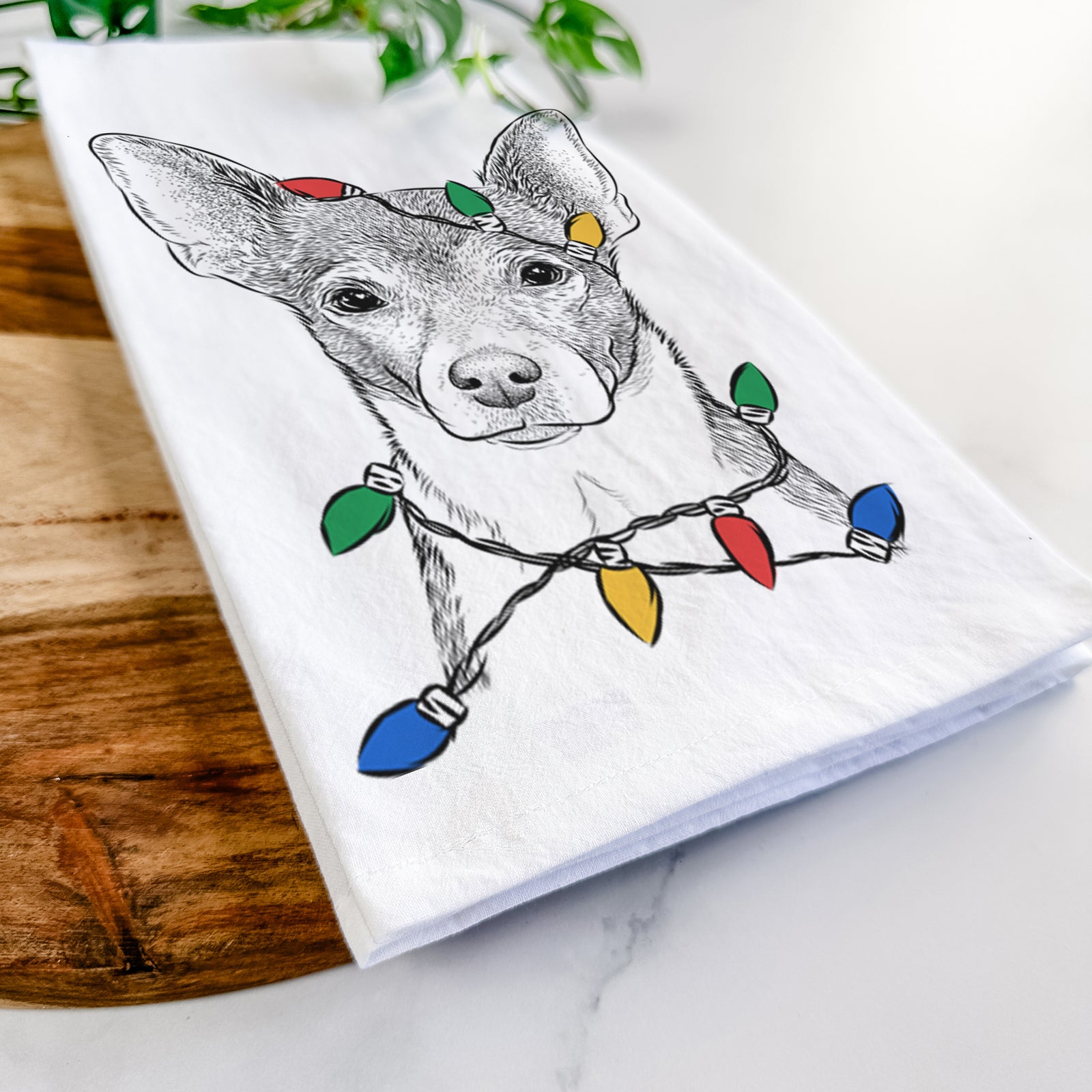 Hand-drawn sketch of Peanut the Chihuahua wrapped in Christmas lights on a tea towel