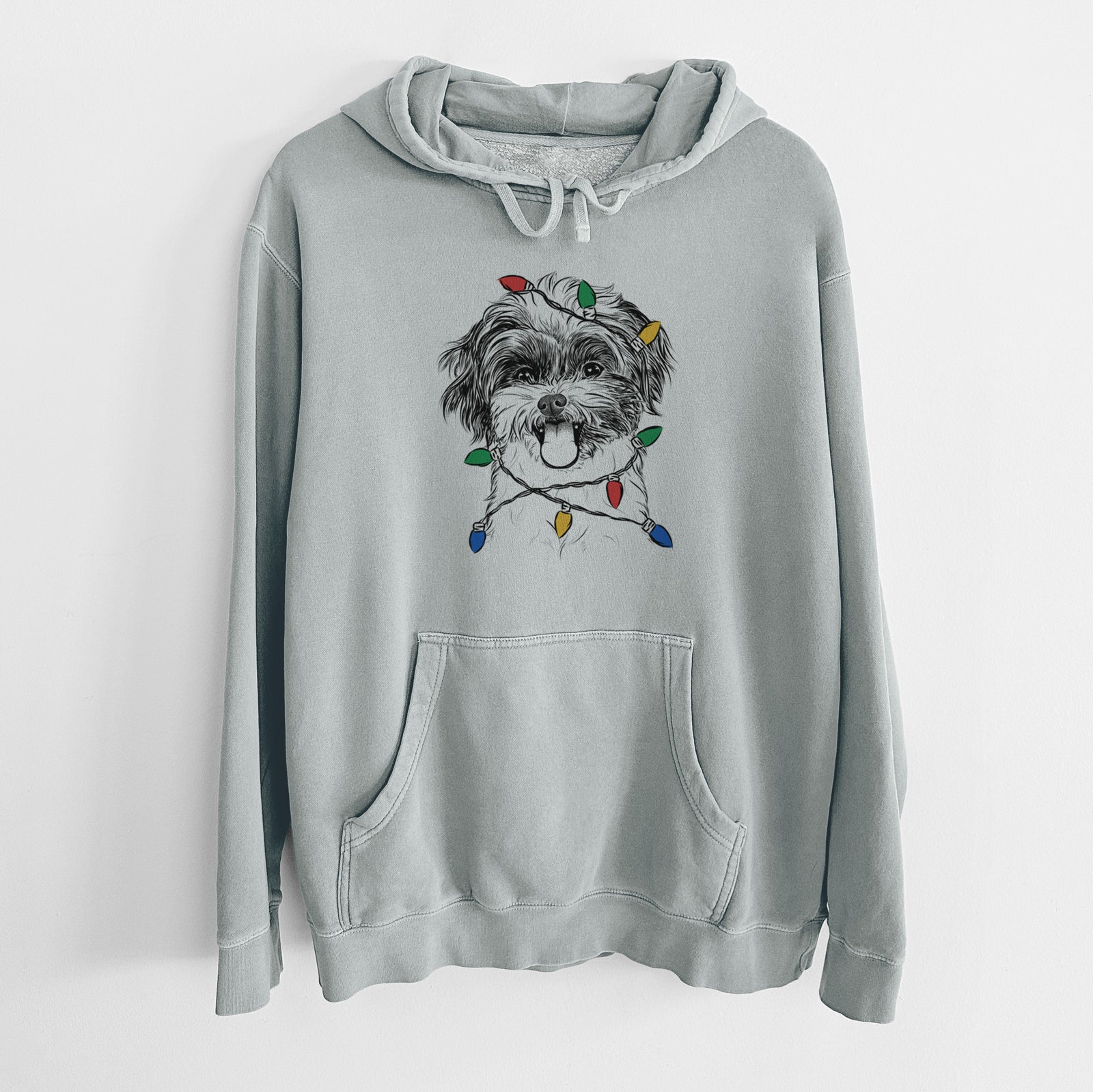 Hand-drawn sketch of Pepper the Shihpoo wrapped in Christmas lights on a Sage Unisex pigment dyed hoodie