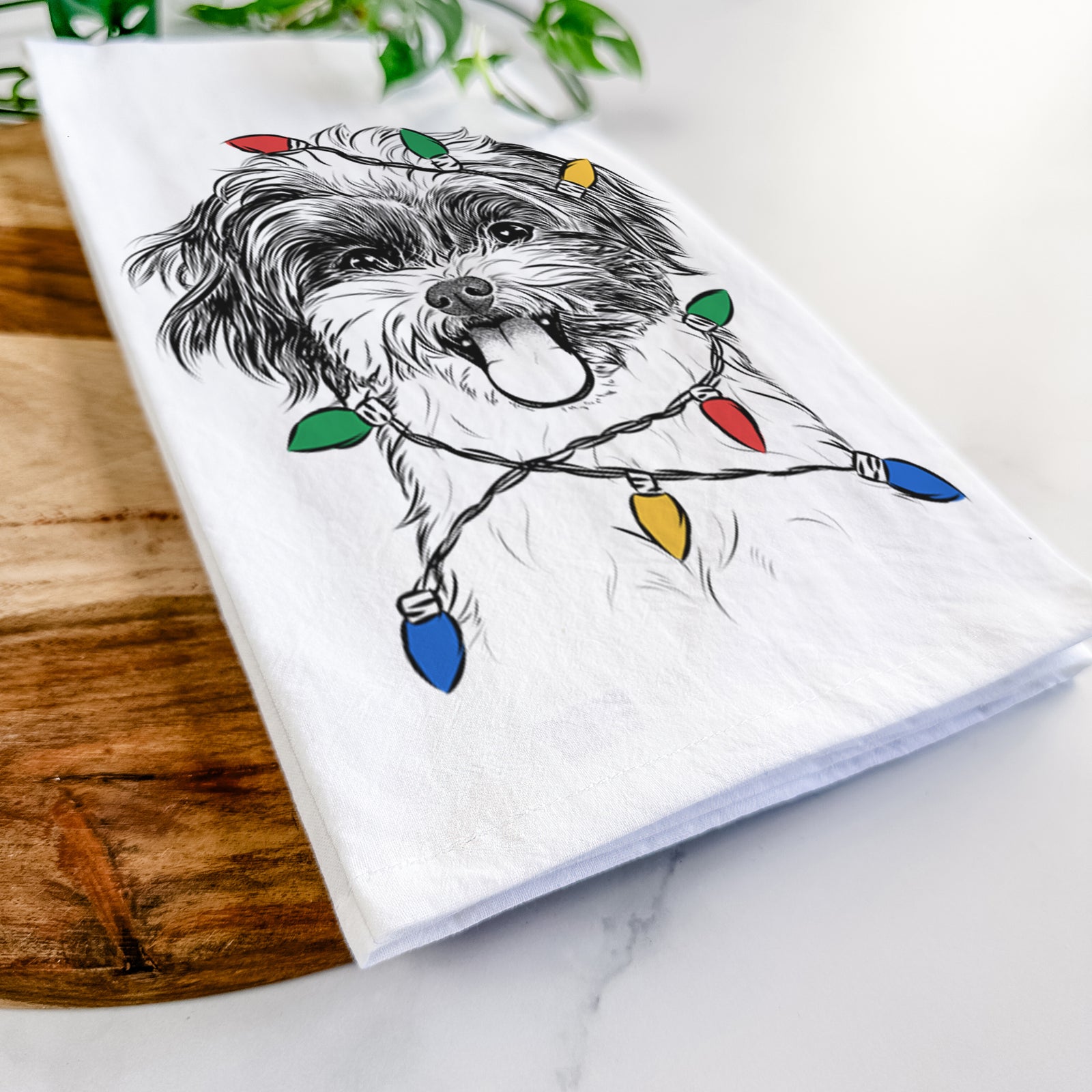 Hand-drawn sketch of Pepper the Shihpoo wrapped in Christmas lights on a tea towel