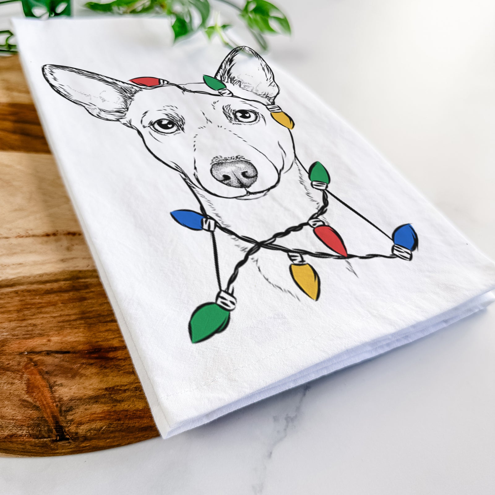 Hand-drawn sketch of Perry the Portuguese Podengo wrapped in Christmas lights on a tea towel
