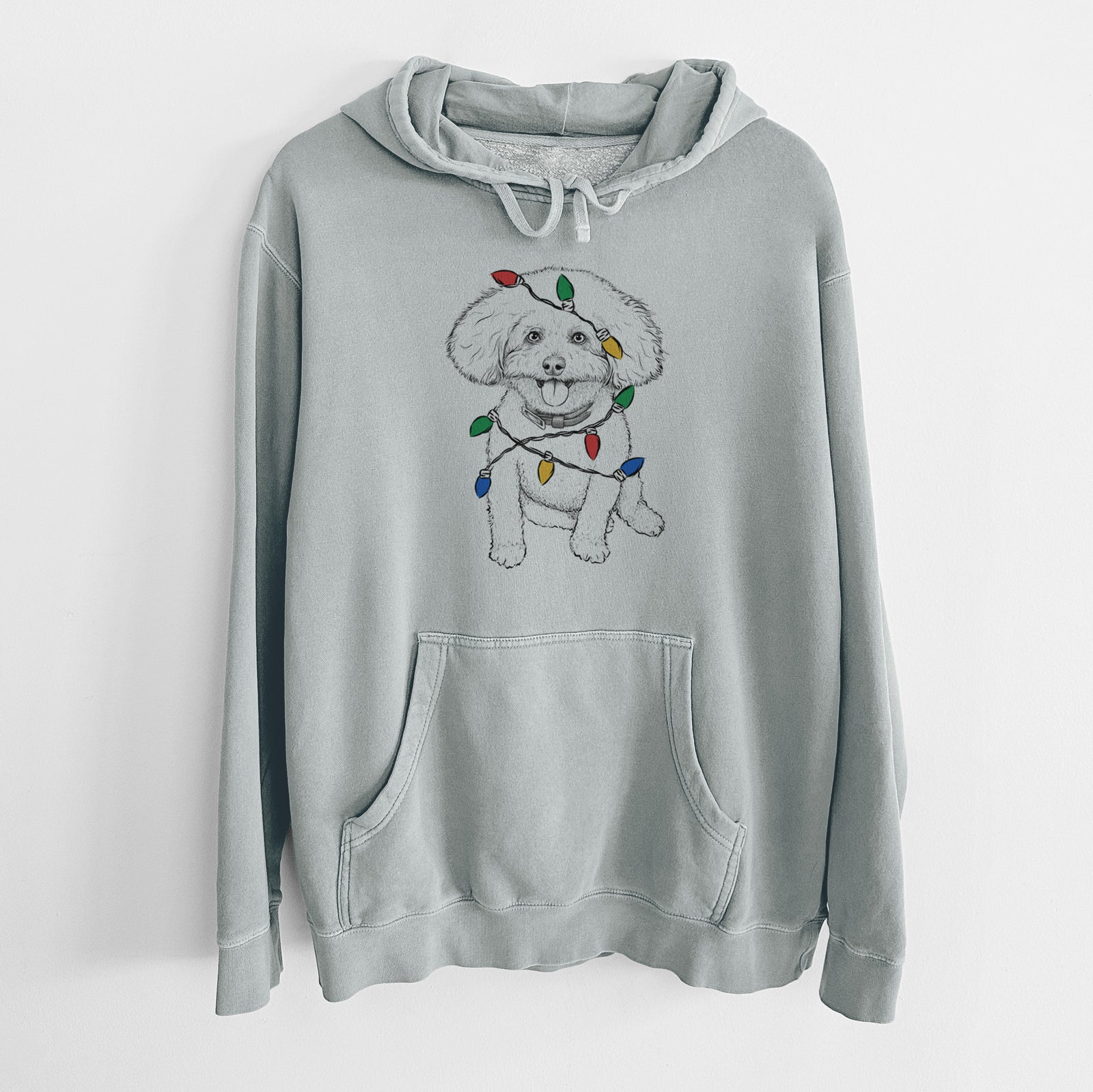 Hand-drawn sketch of Peyton the Bichon Frise wrapped in Christmas lights on a Sage Unisex pigment dyed hoodie