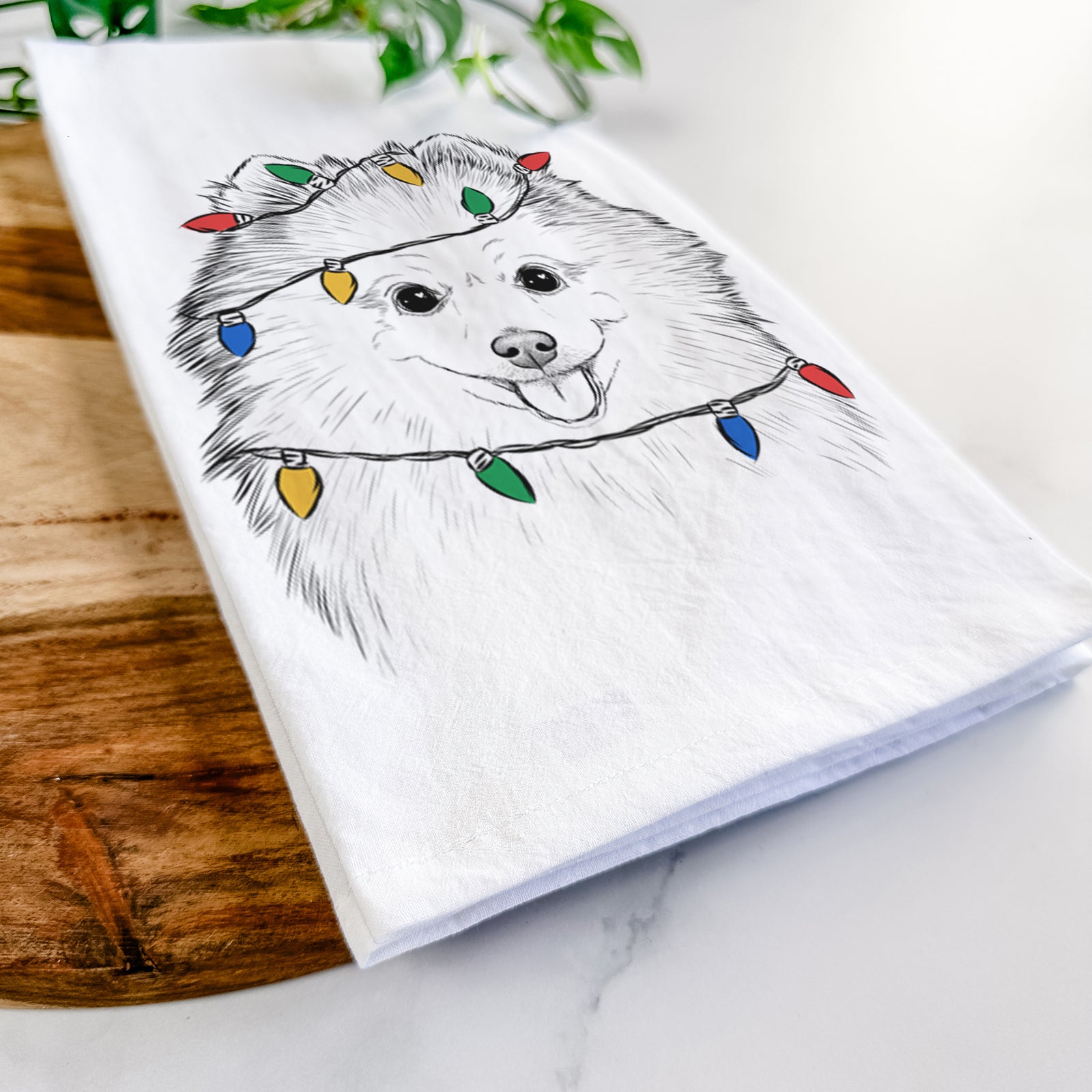 Hand-drawn sketch of Piper Jo the Pomeranian wrapped in Christmas lights on a tea towel