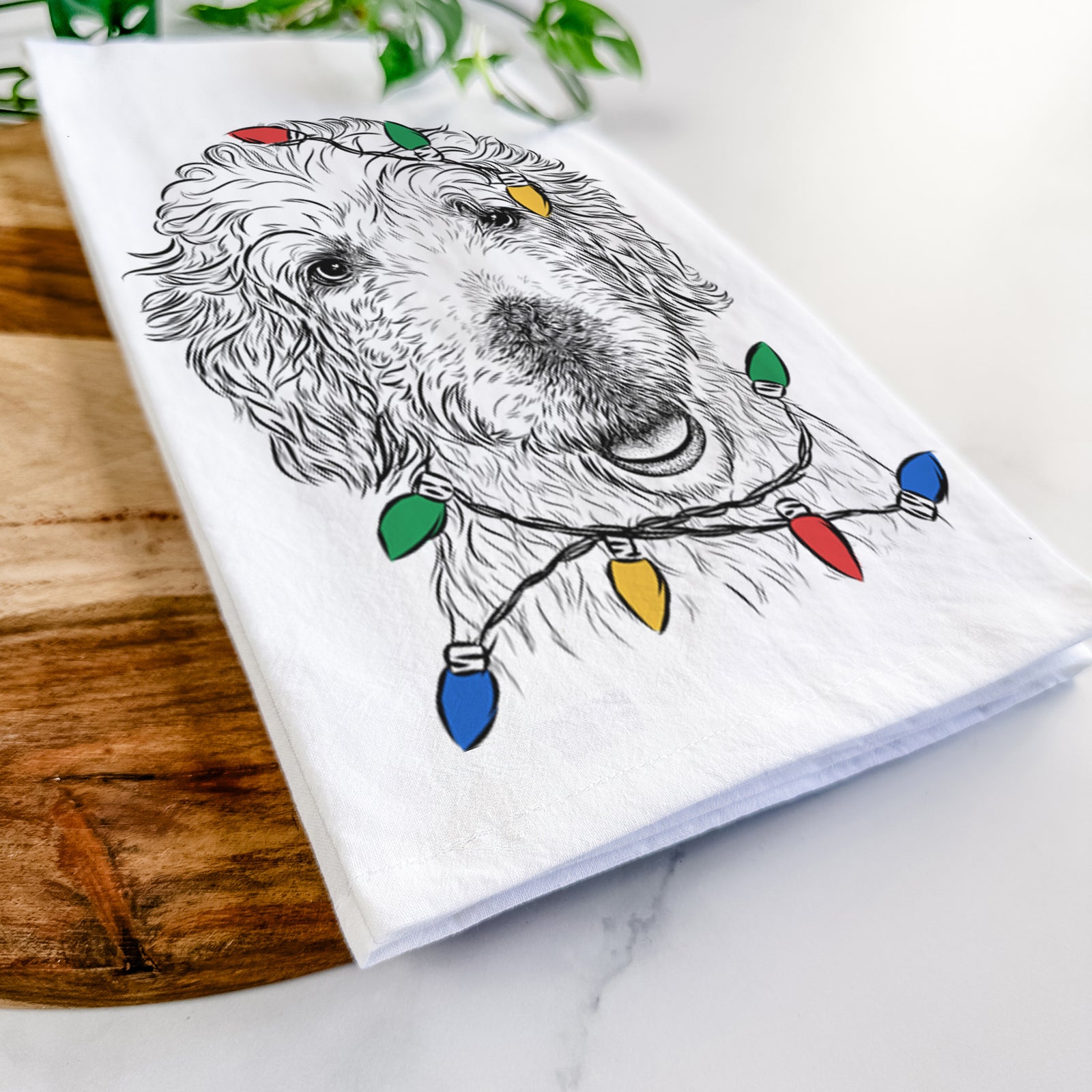 Hand-drawn sketch of Preston the Labradoodle wrapped in Christmas lights on a tea towel