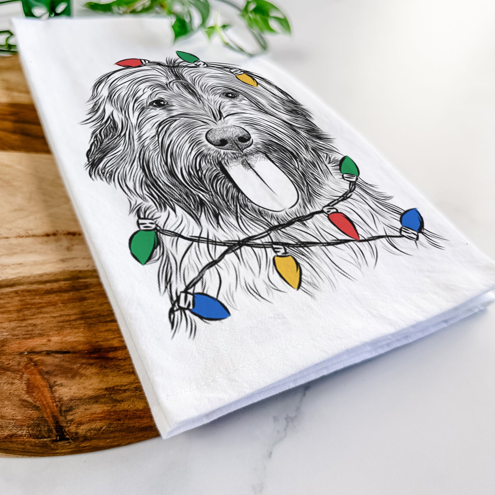 Hand-drawn sketch of Puig the Catalan Sheepdog wrapped in Christmas lights on a tea towel