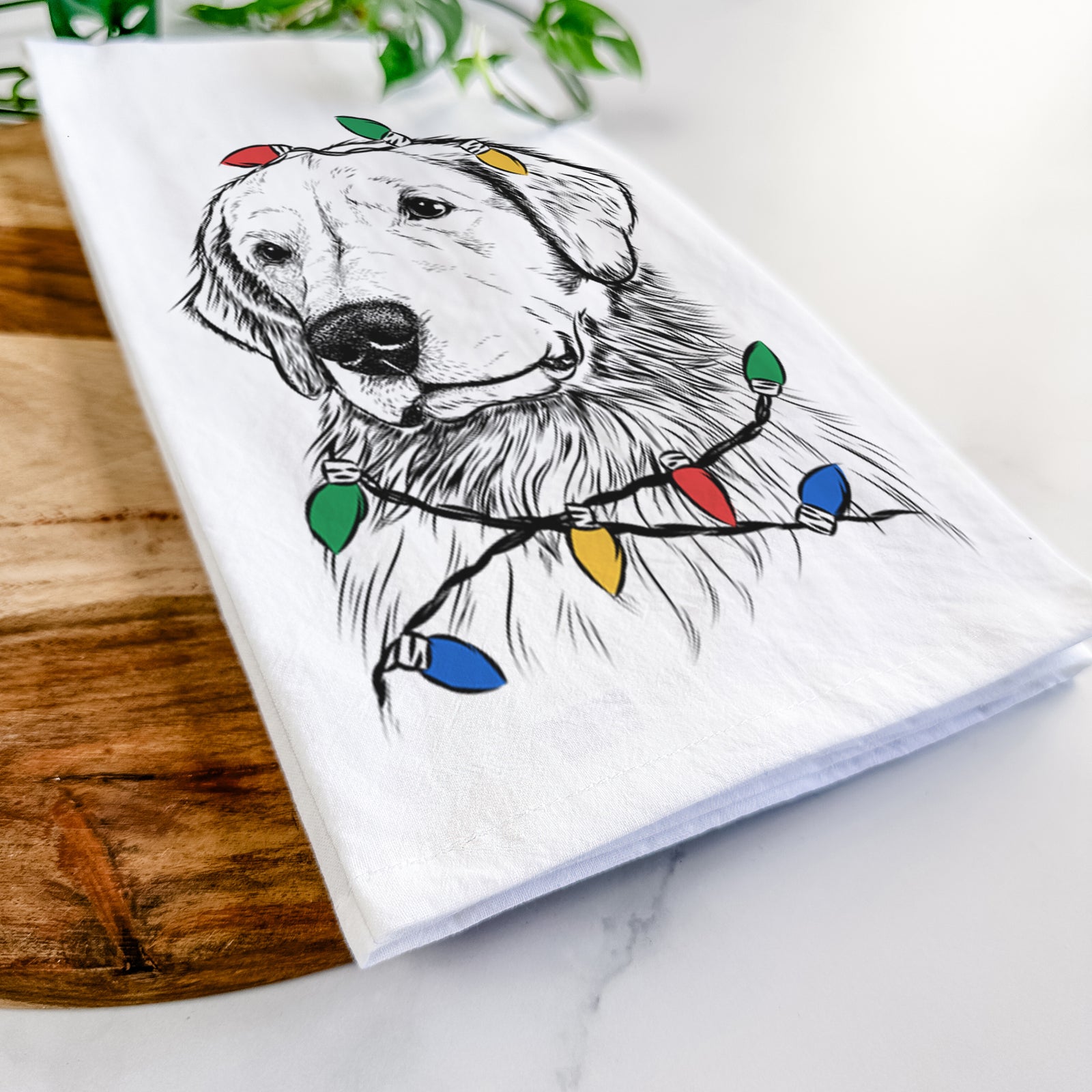 Hand-drawn sketch of Quinn the Golden Retriever wrapped in Christmas lights on a tea towel