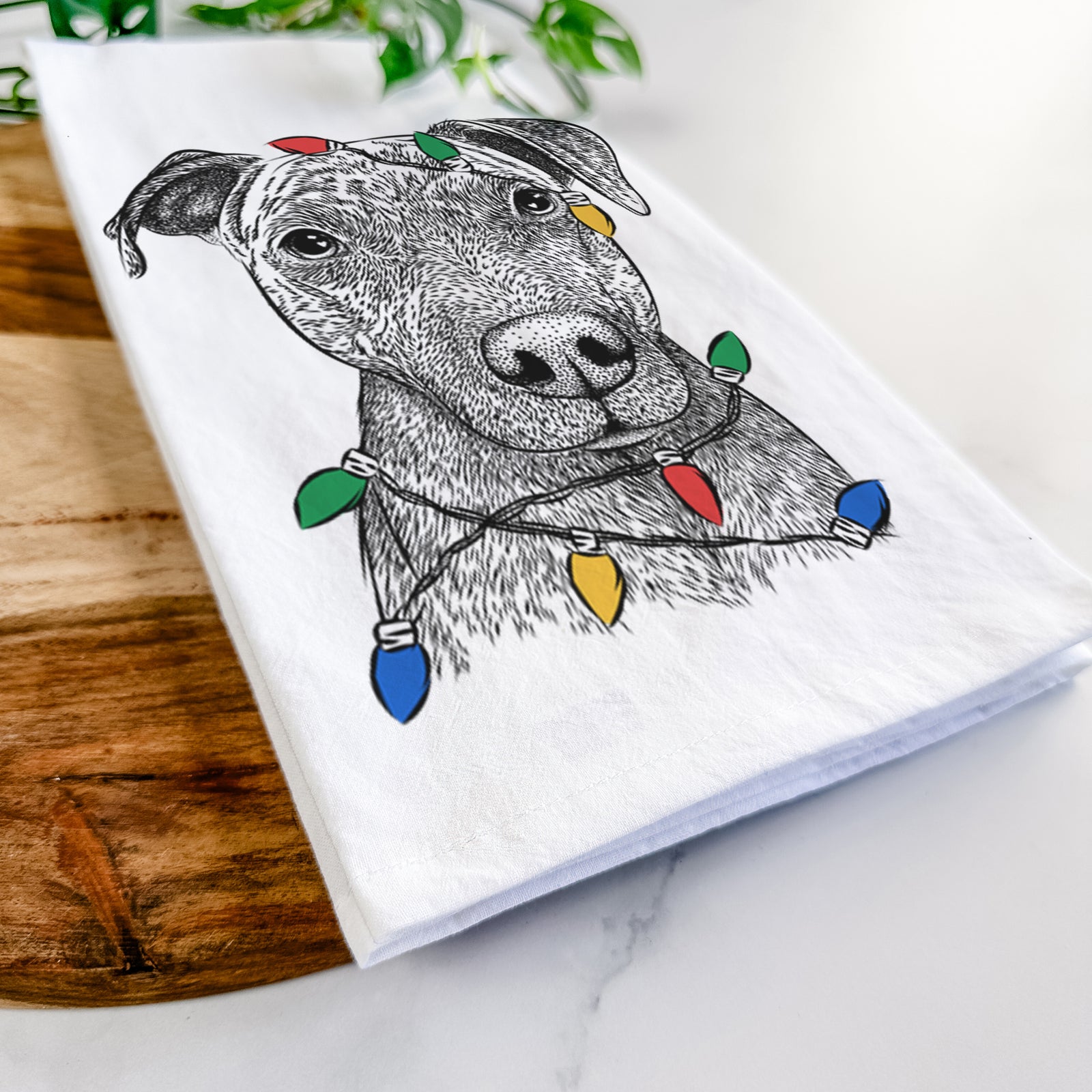 Hand-drawn sketch of Reeses the Pitbull wrapped in Christmas lights on a tea towel