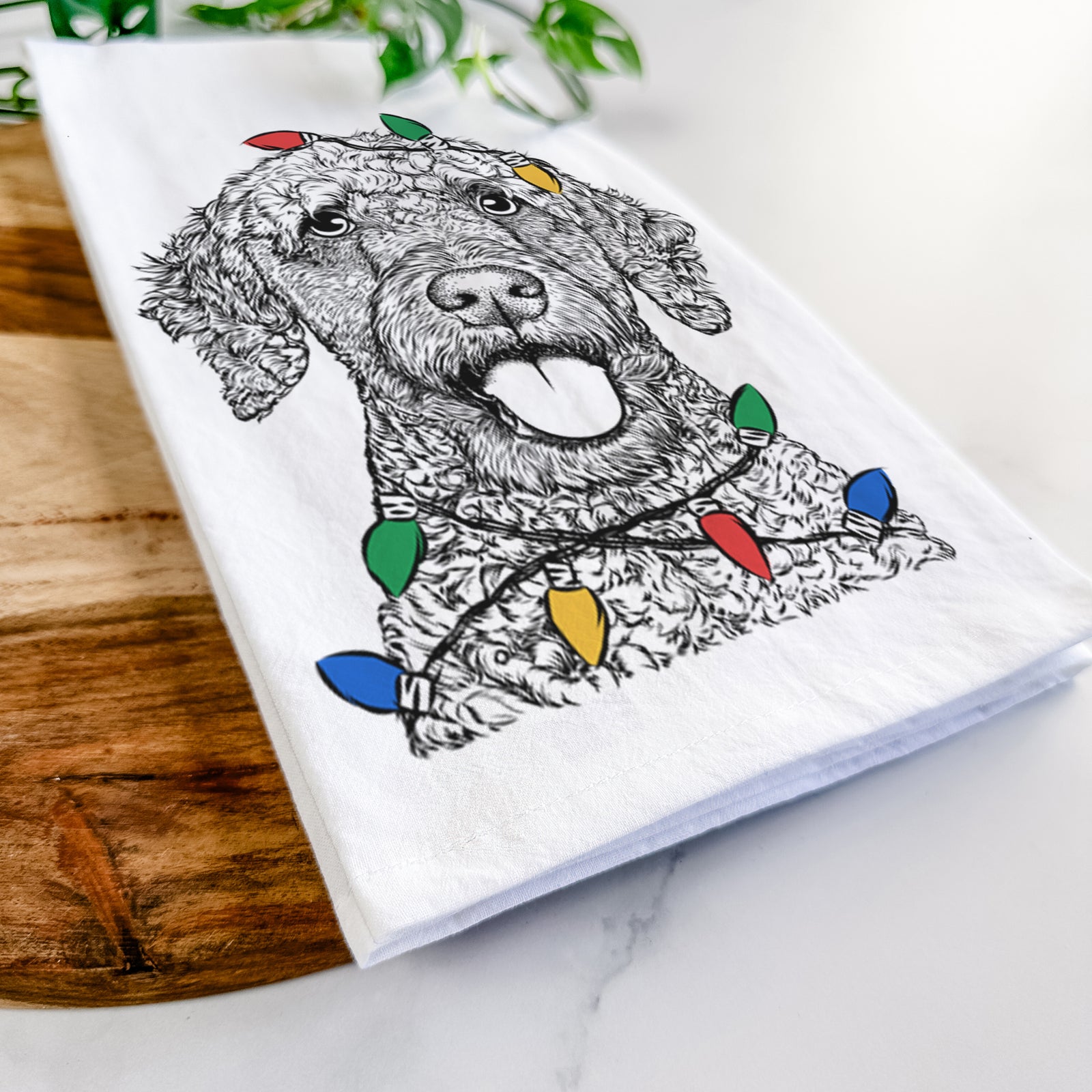 Hand-drawn sketch of Reina the Spanish Water Dog wrapped in Christmas lights on a tea towel