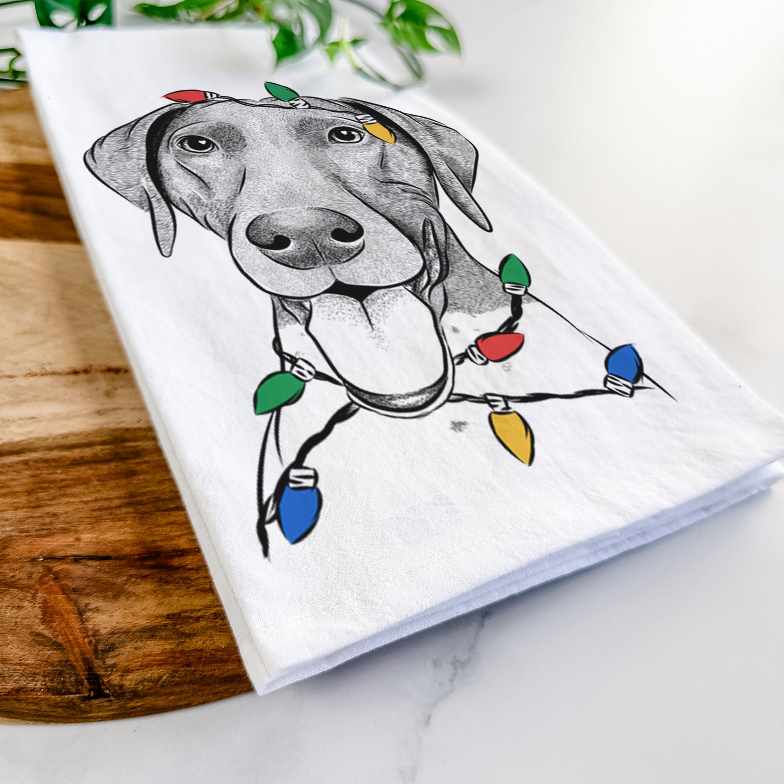 Hand-drawn sketch of Remi the German Shorthaired Pointer wrapped in Christmas lights on a tea towel