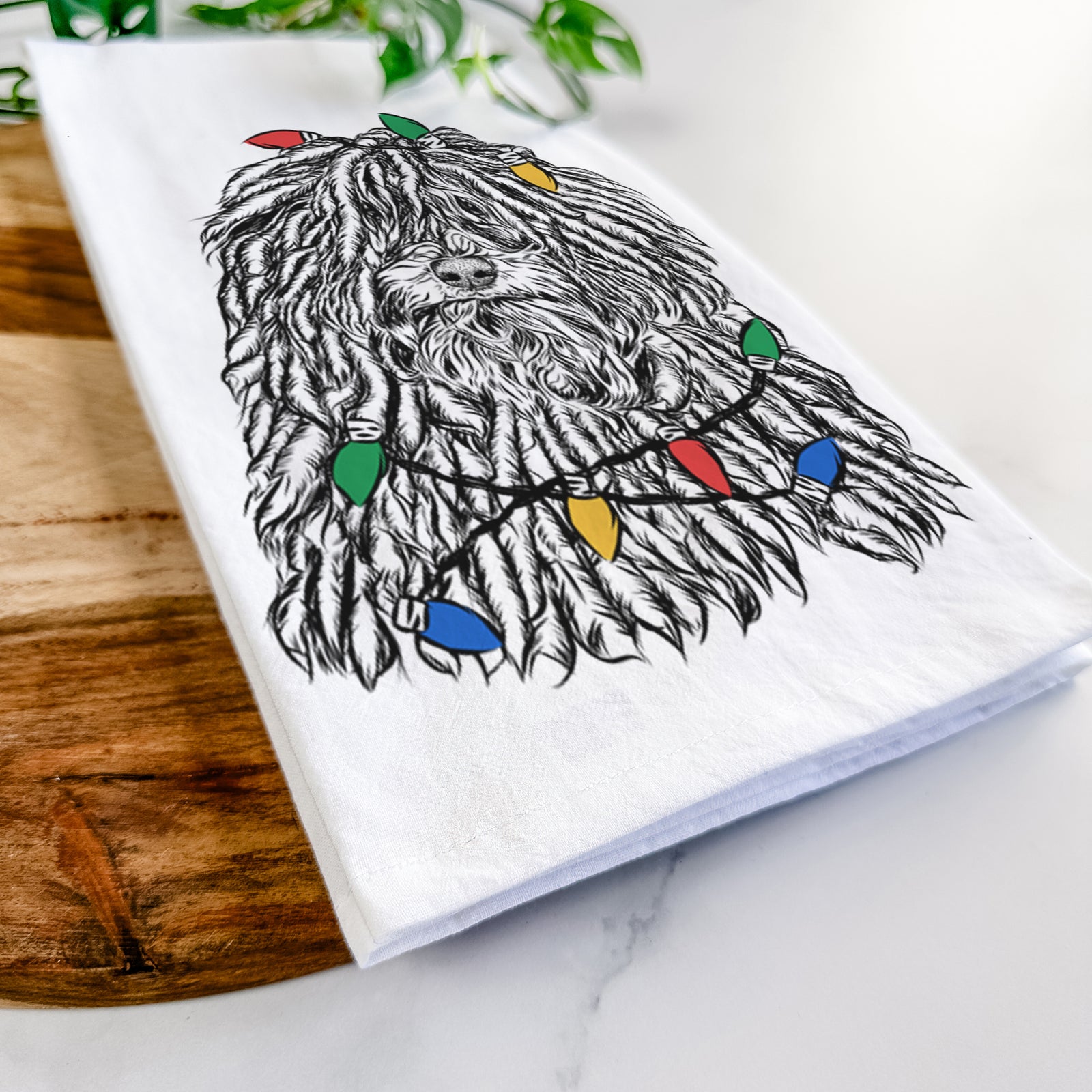 Hand-drawn sketch of Rezi the Puli wrapped in Christmas lights on a tea towel