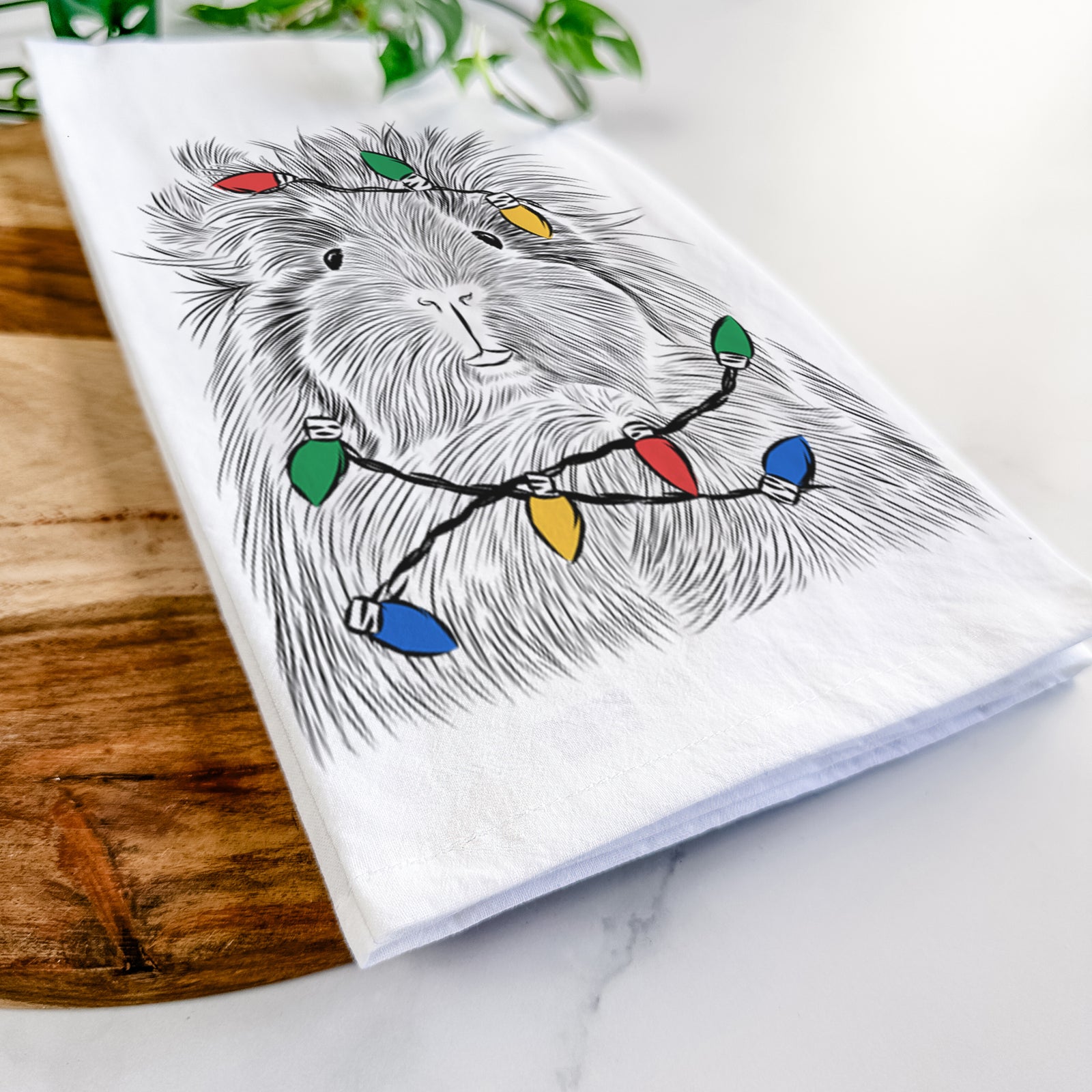 Hand-drawn sketch of Rhino the Guinea Pig wrapped in Christmas lights on a tea towel
