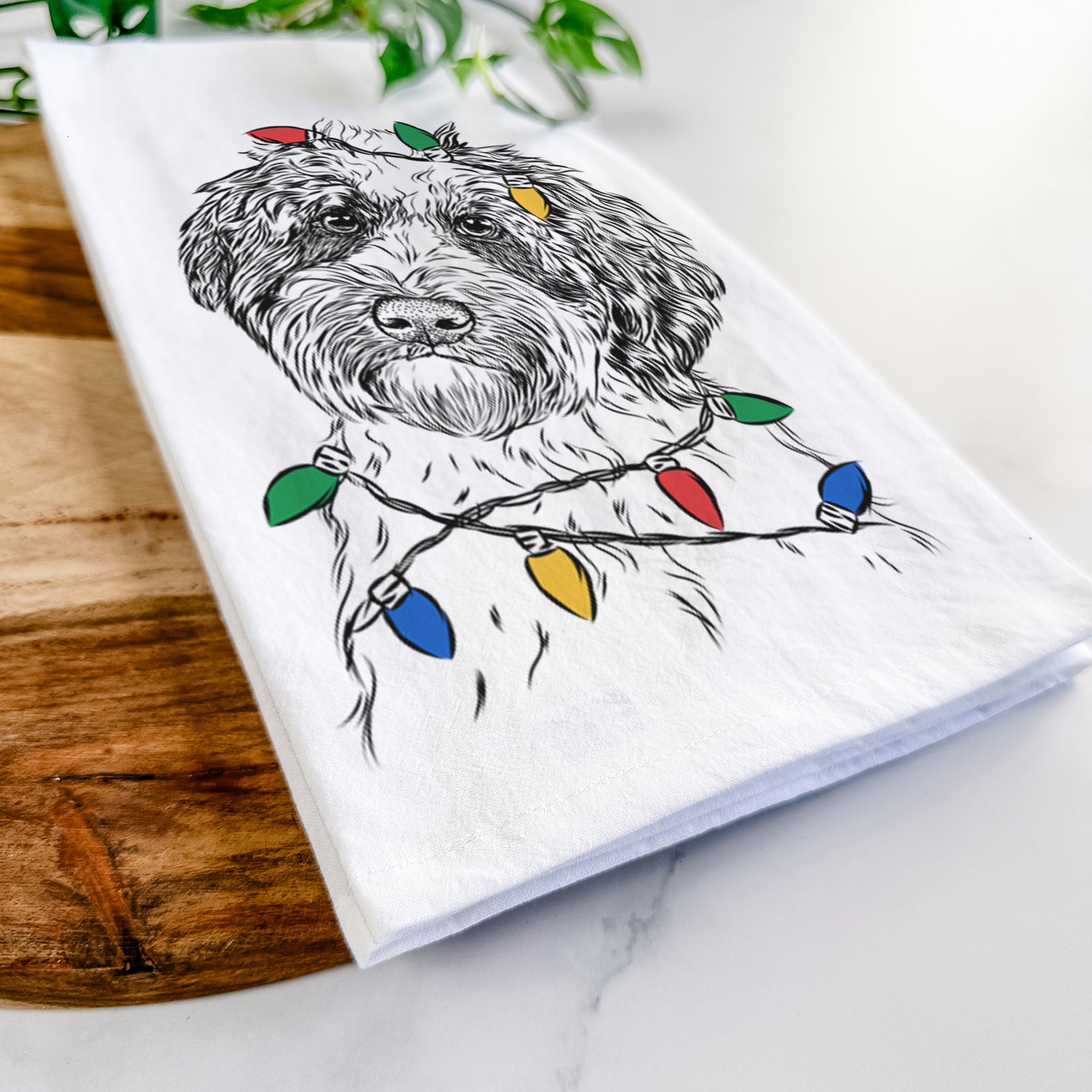 Hand-drawn sketch of Rooney the Aussiedoodle wrapped in Christmas lights on a tea towel