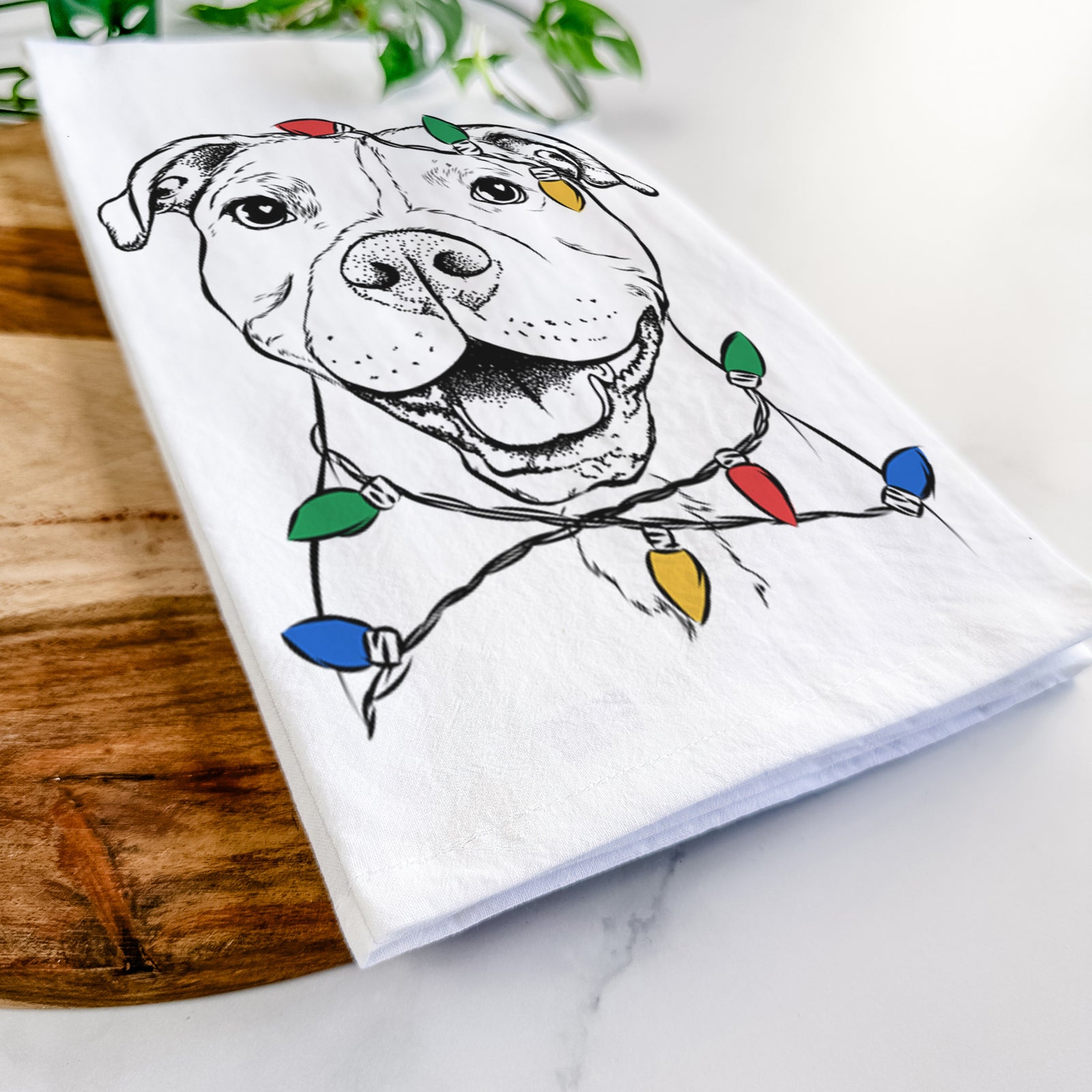Hand-drawn sketch of Roscoe the Pitbull wrapped in Christmas lights on a tea towel