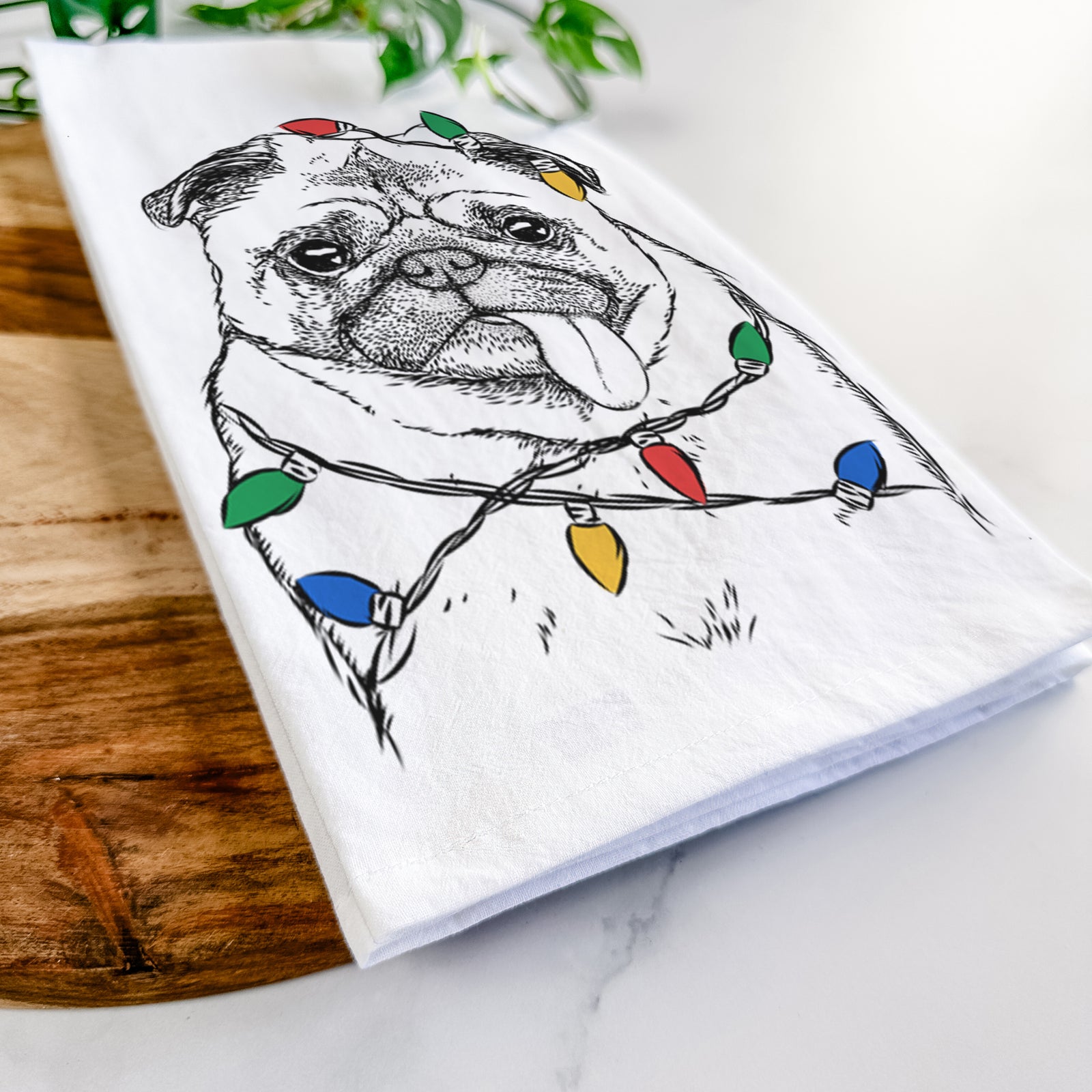 Hand-drawn sketch of Rosie the Pug wrapped in Christmas lights on a tea towel