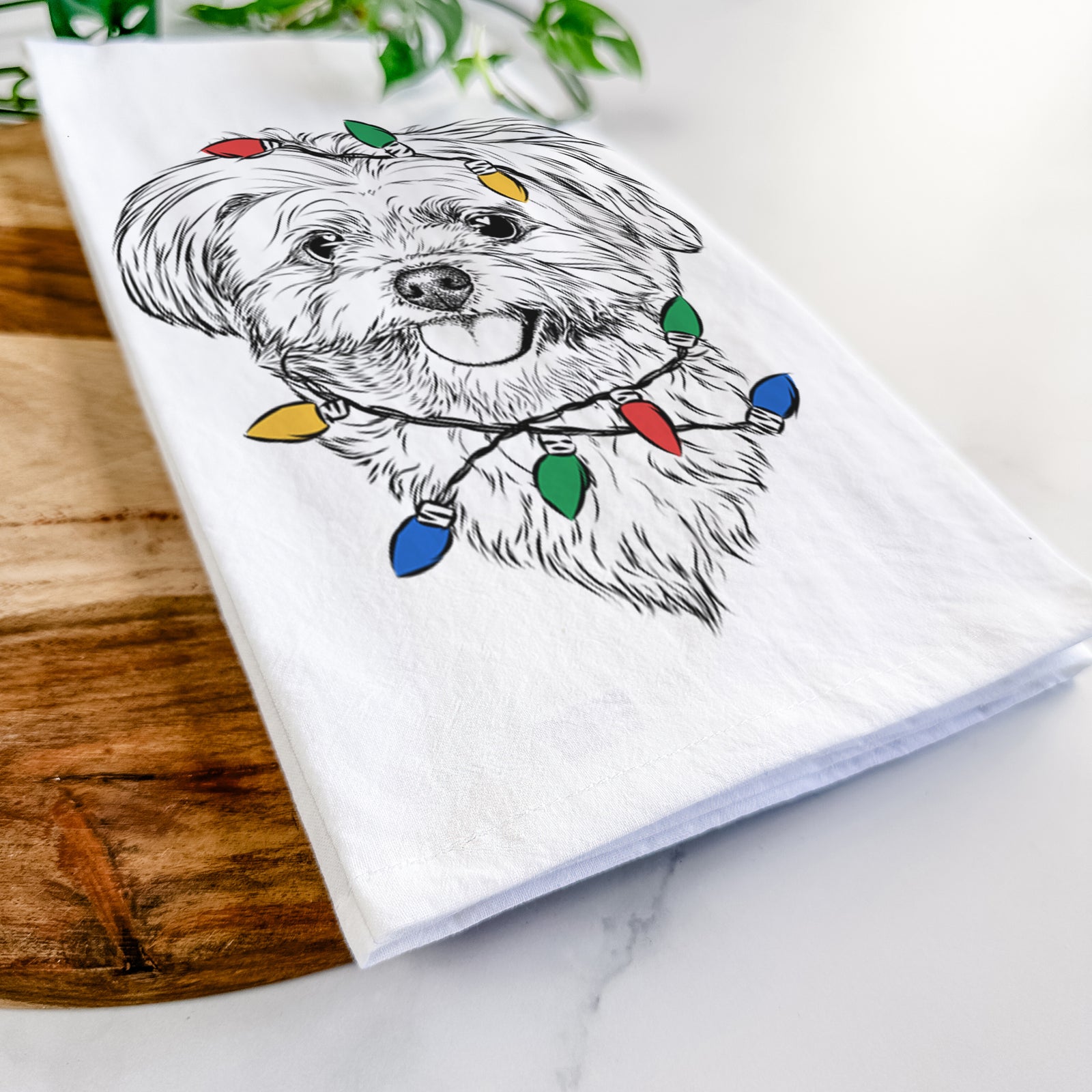 Hand-drawn sketch of Rosie the Maltipoo wrapped in Christmas lights on a tea towel