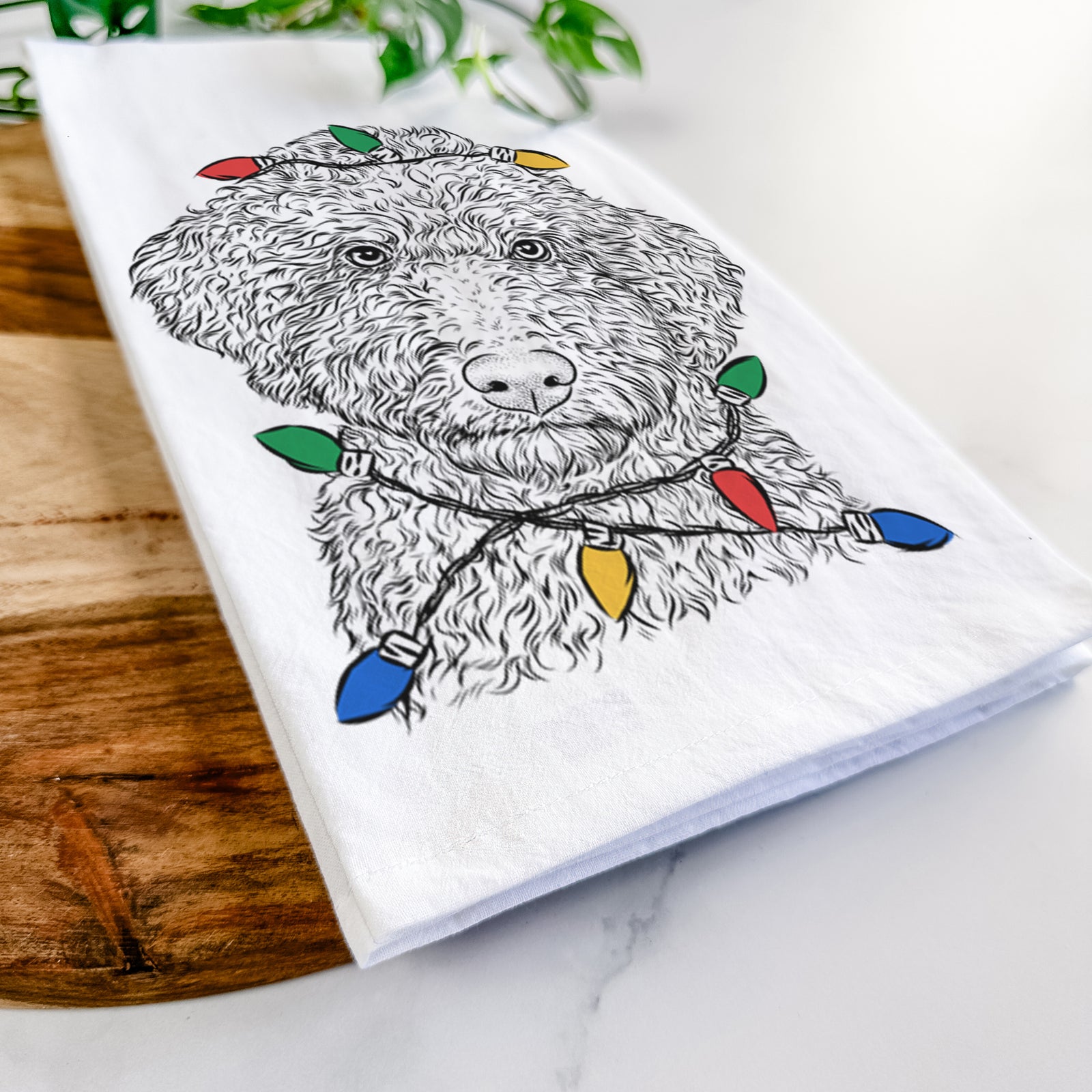 Hand-drawn sketch of Ross the Lagotto Romagnolo wrapped in Christmas lights on a tea towel