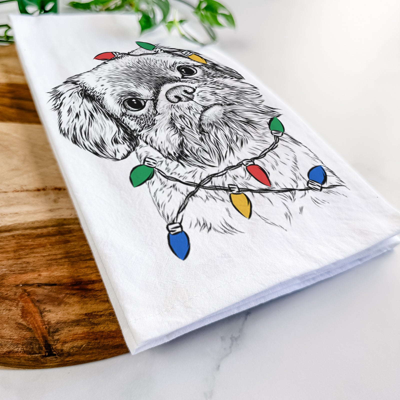 Hand-drawn sketch of Rufus the Shiffon wrapped in Christmas lights on a tea towel