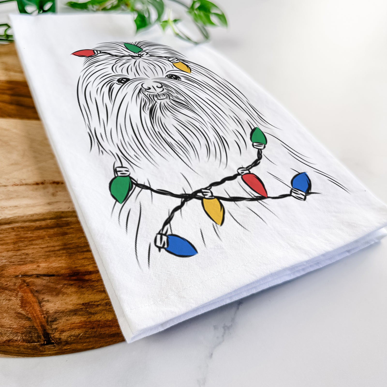 Hand-drawn sketch of Sabine the Shih Tzu wrapped in Christmas lights on a tea towel