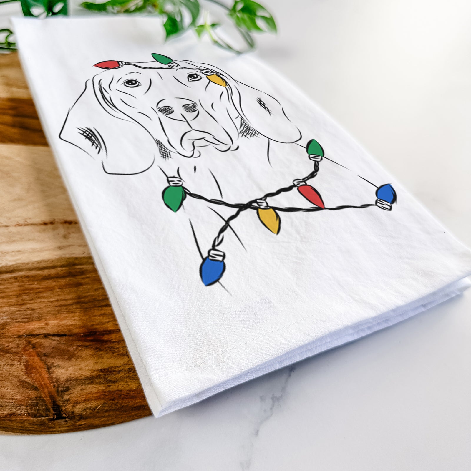 Hand-drawn sketch of Sagan the Coonhound wrapped in Christmas lights on a tea towel