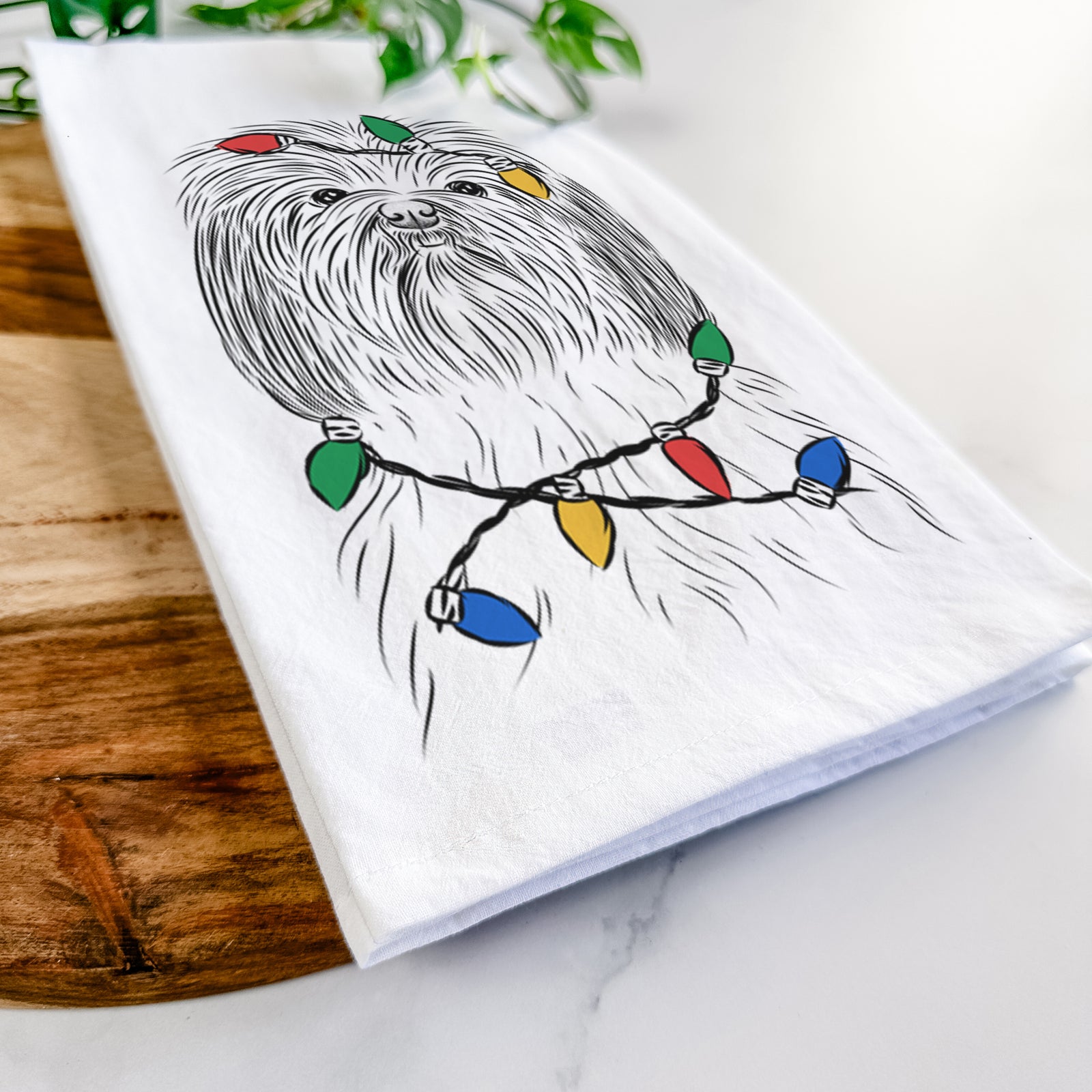 Hand-drawn sketch of Scully the Shih Tzu wrapped in Christmas lights on a tea towel