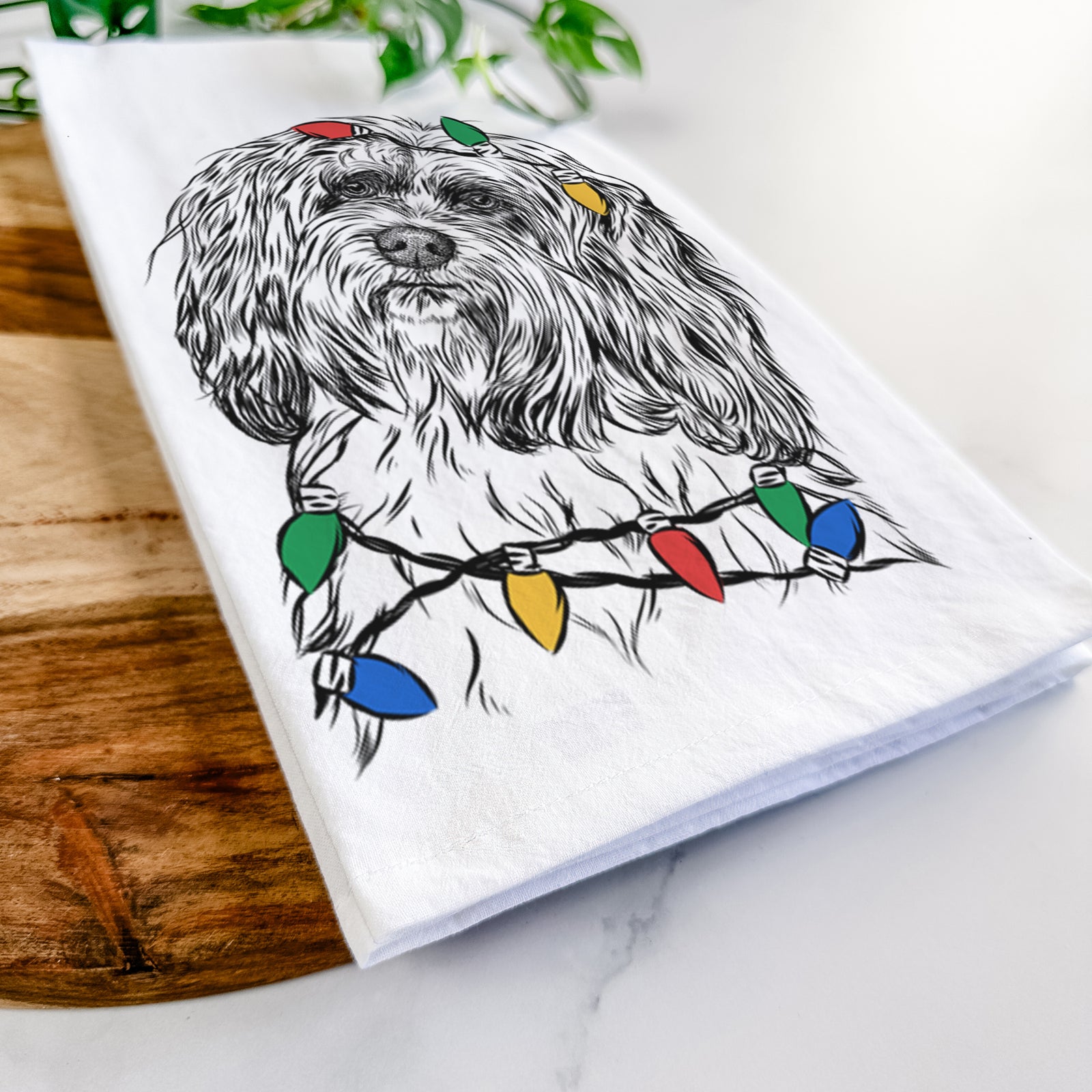 Hand-drawn sketch of Shenpa the Tibetan Terrier wrapped in Christmas lights on a tea towel