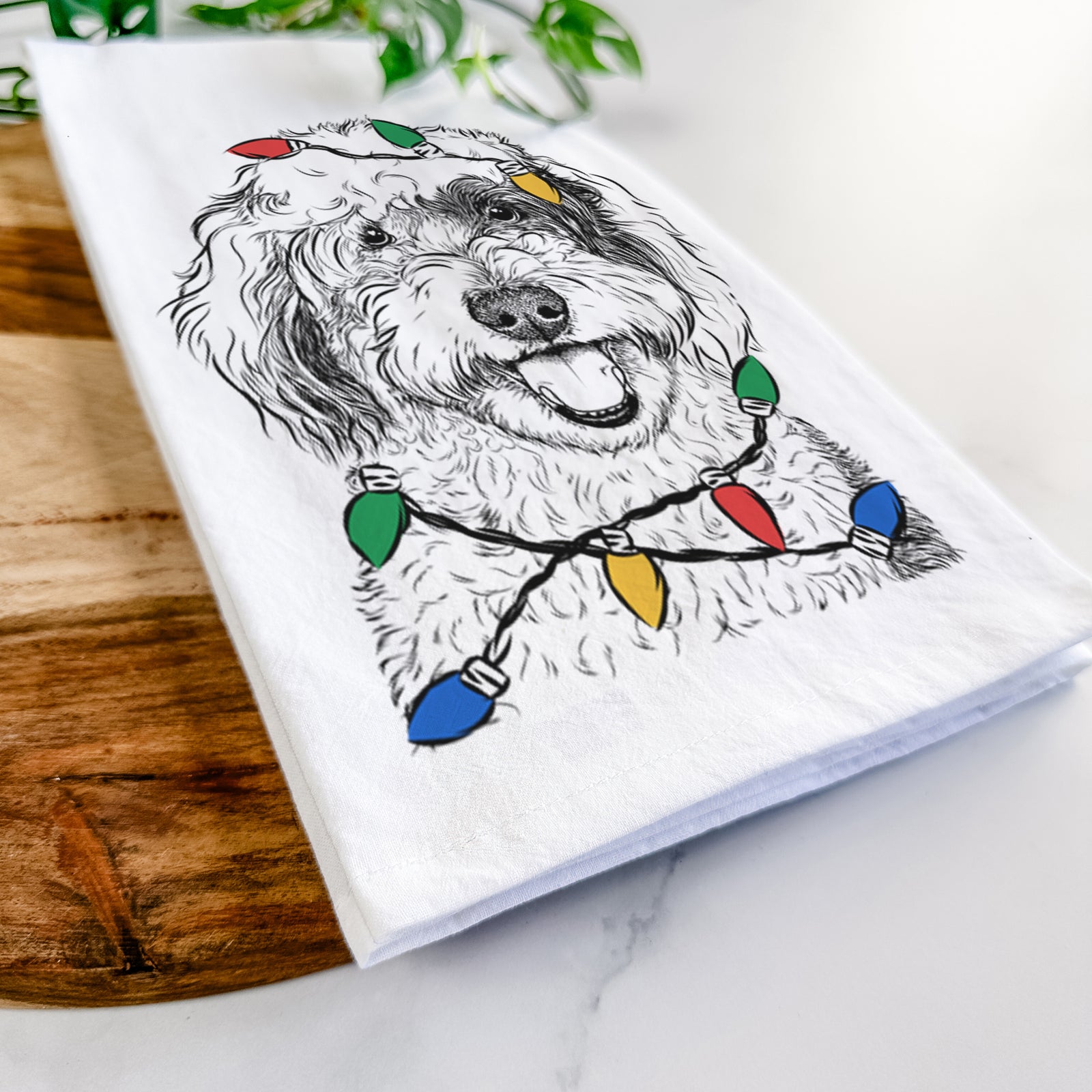 Hand-drawn sketch of Sherlock the Sheepadoodle wrapped in Christmas lights on a tea towel