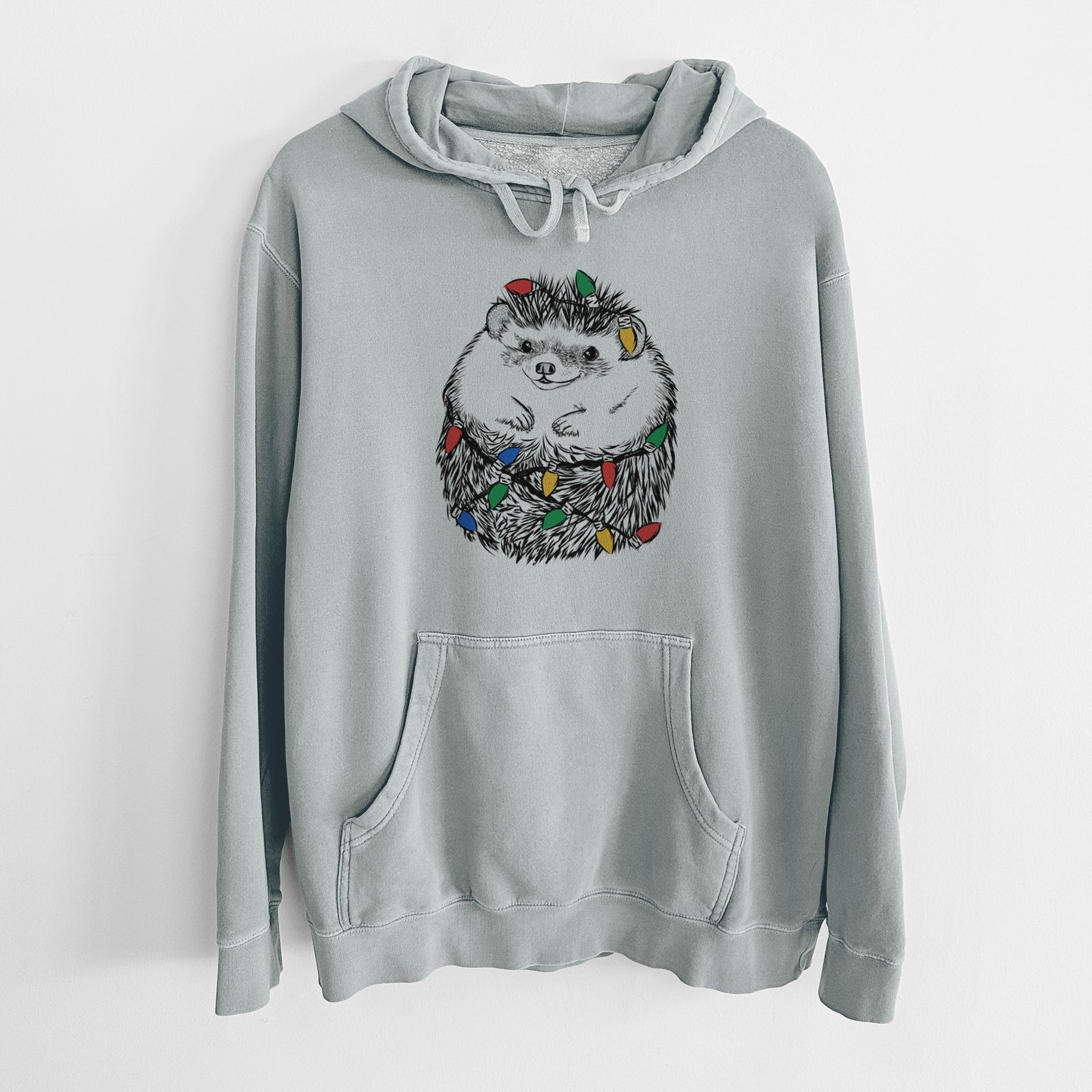 Hand-drawn sketch of Sid the Hedgehog wrapped in Christmas lights on a Sage Unisex pigment dyed hoodie