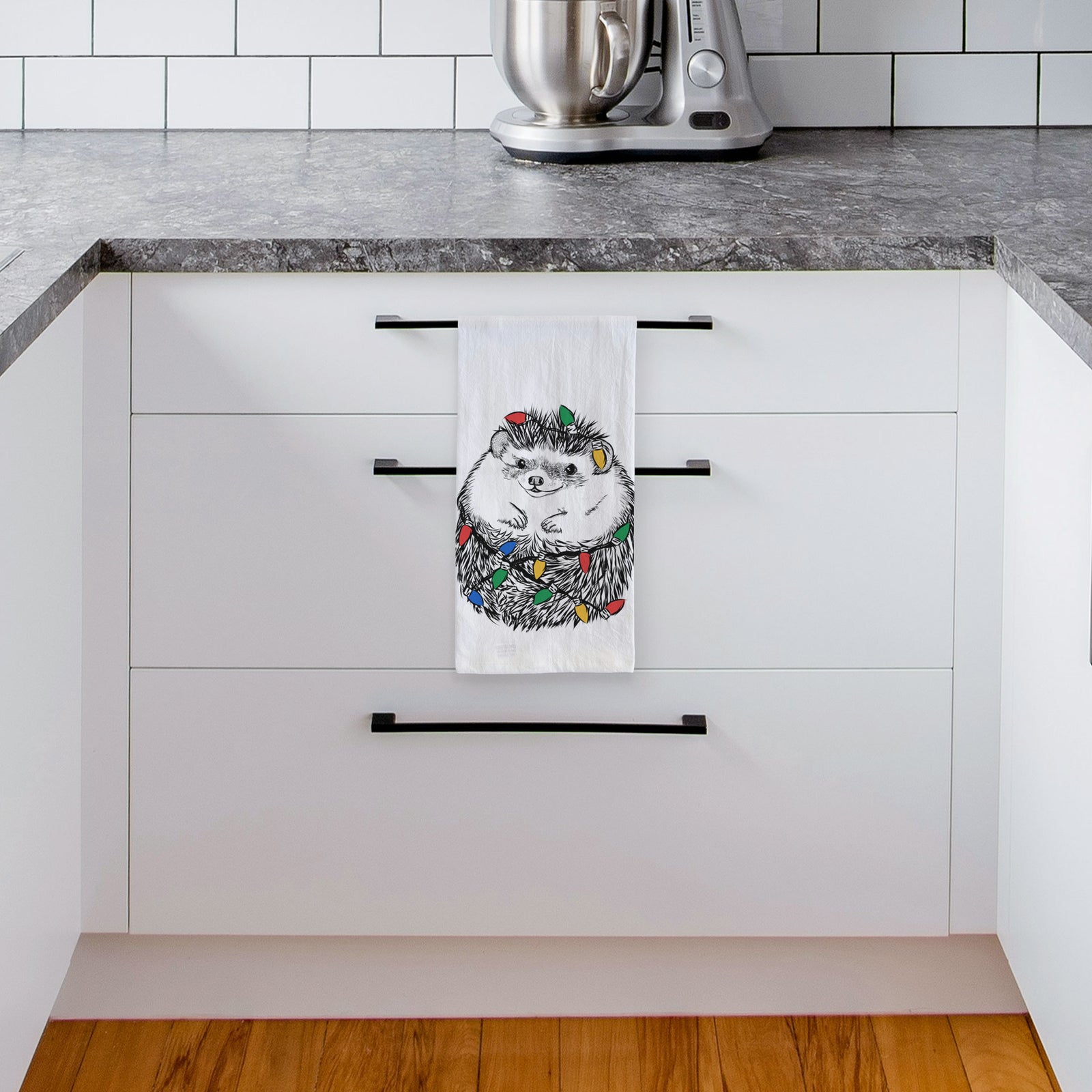 Hand-drawn sketch of Sid the Hedgehog wrapped in Christmas lights on a tea towel, hanging on an oven door in a kitchen