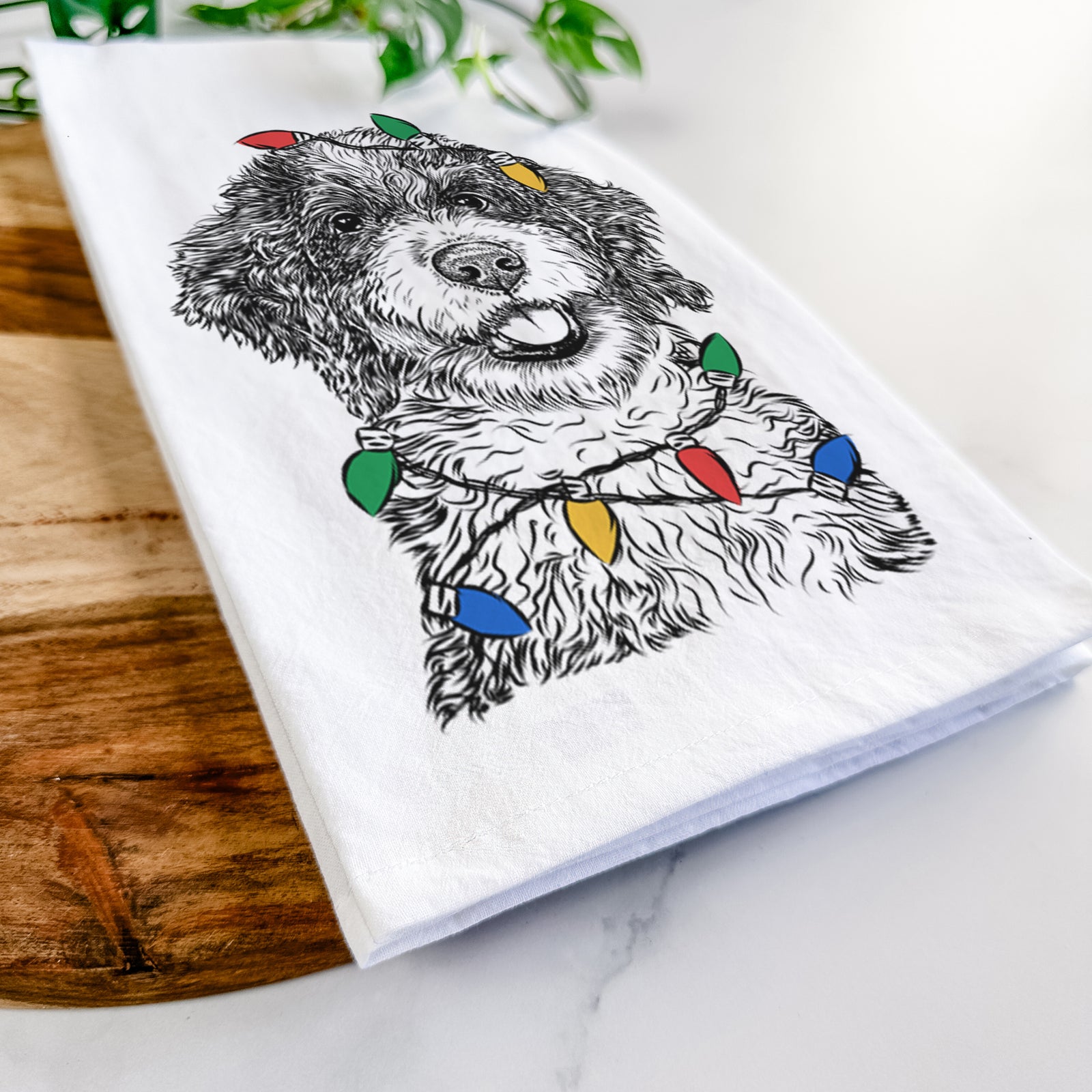 Hand-drawn sketch of Smoky the Bernedoodle Puppy wrapped in Christmas lights on a tea towel