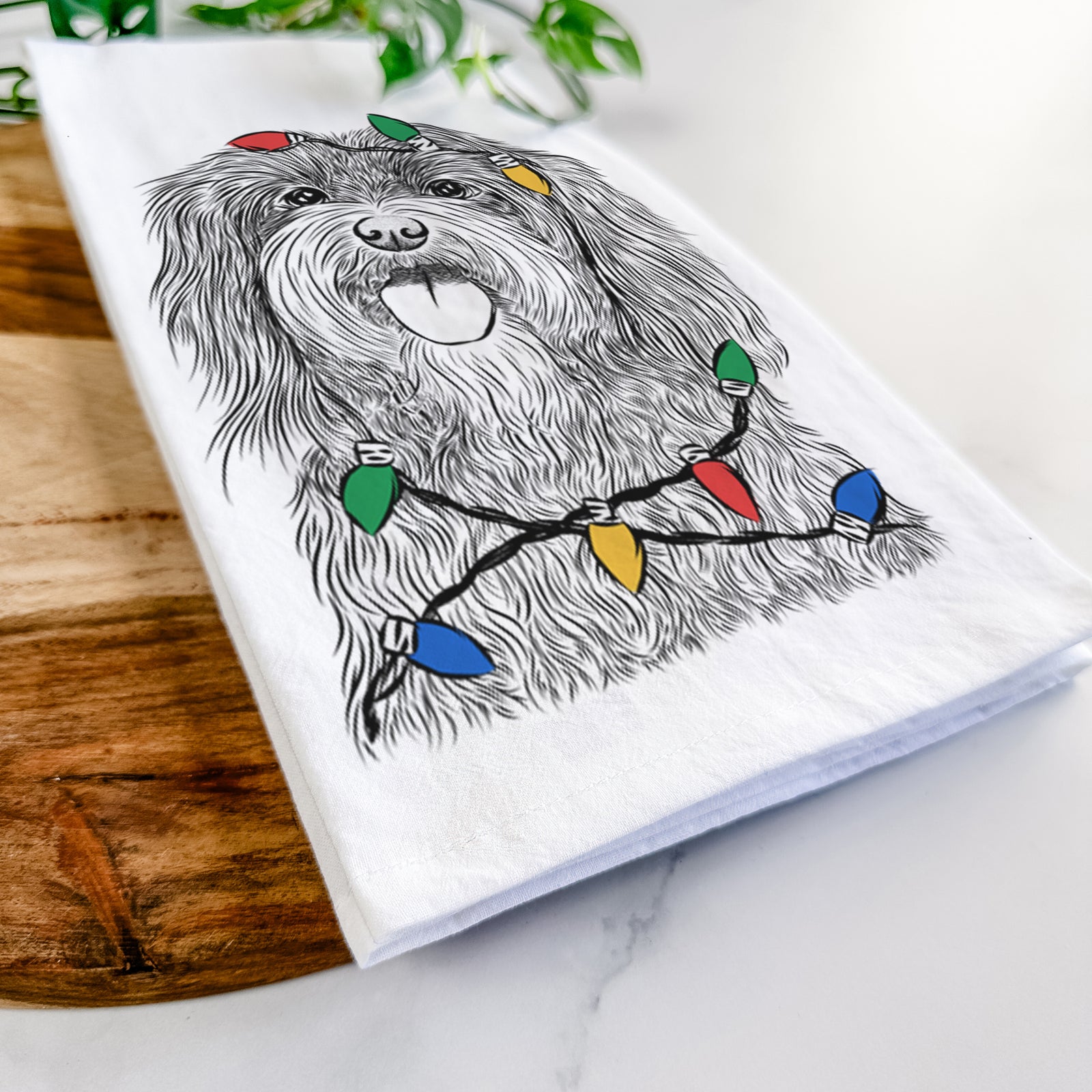 Hand-drawn sketch of Sophie the Havanese wrapped in Christmas lights on a tea towel